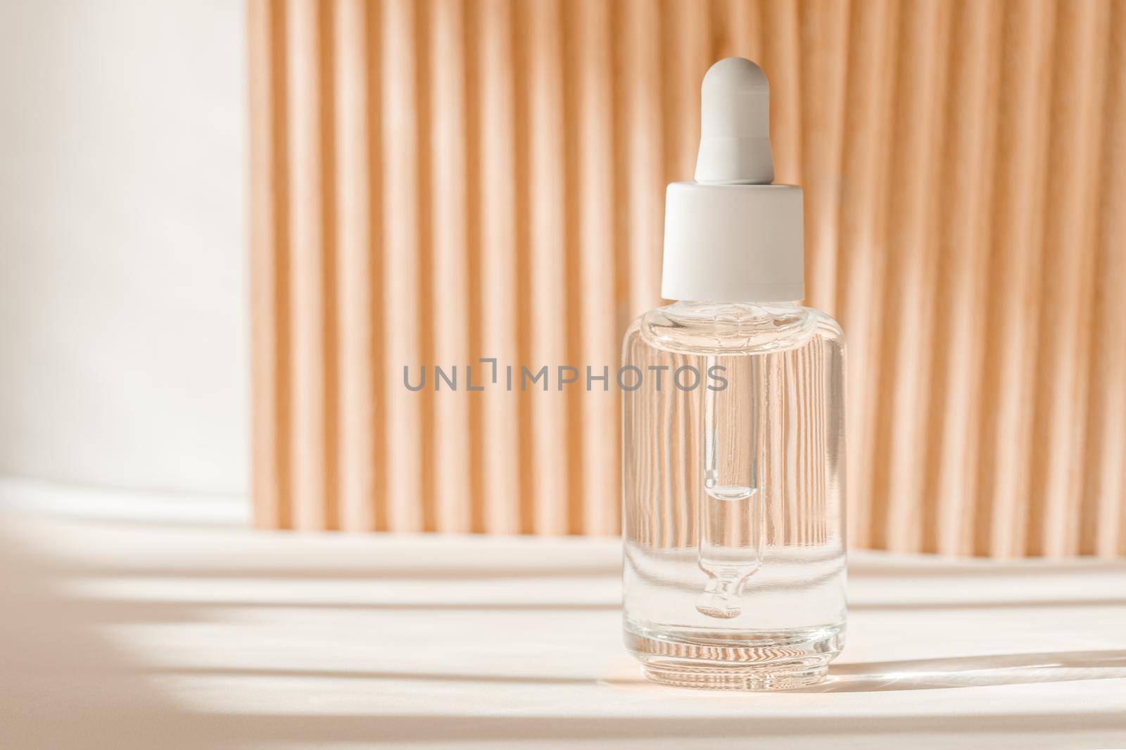 Serum cosmetic bottle, hyaluronic acid on brown background. Serum product with peptide and collagen cosmetics. Cosmetic showcase, art deco, natural shadows. Commercial, modern brand packaging mockup