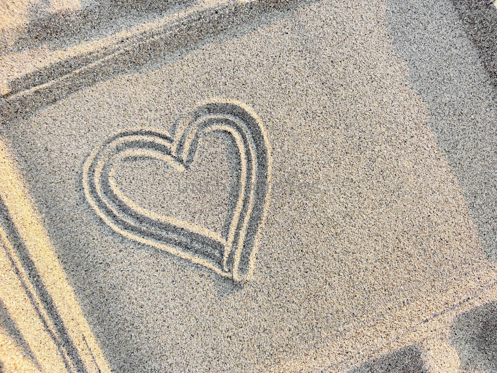 Heart drawn on the sand in a frame, top view, close-up. Copy space.