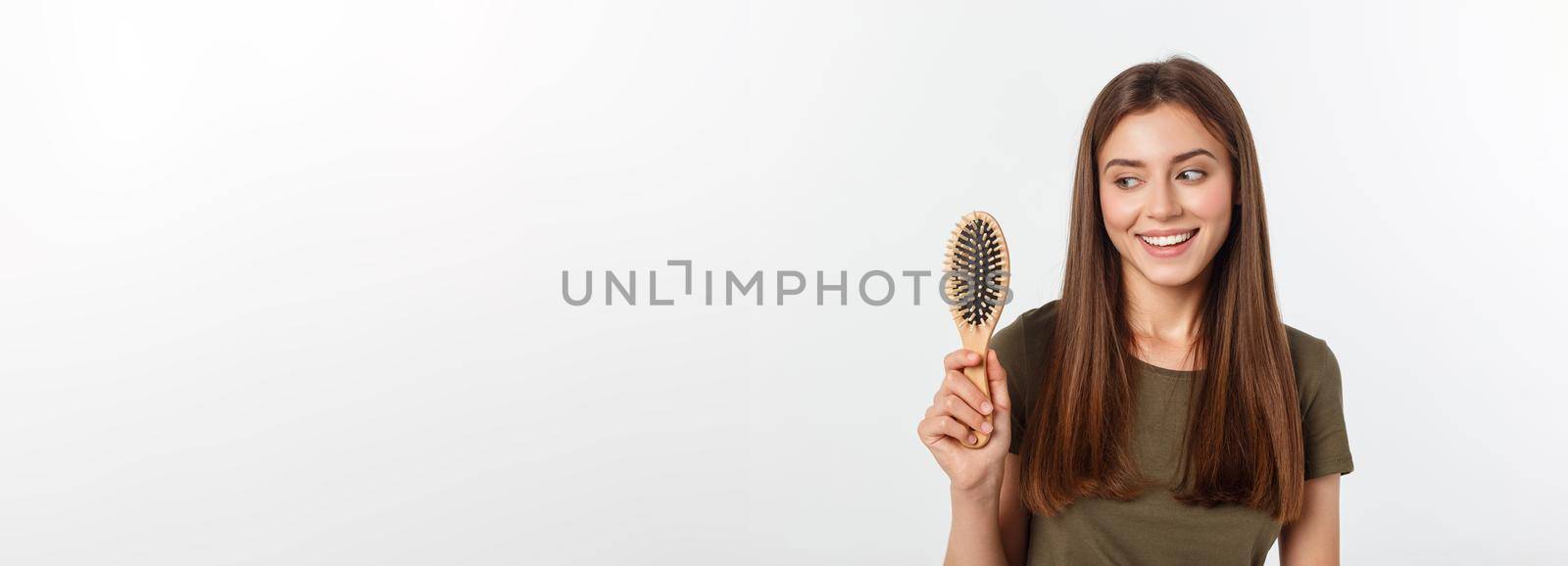 Happy young woman combing her long healthy hair on white background