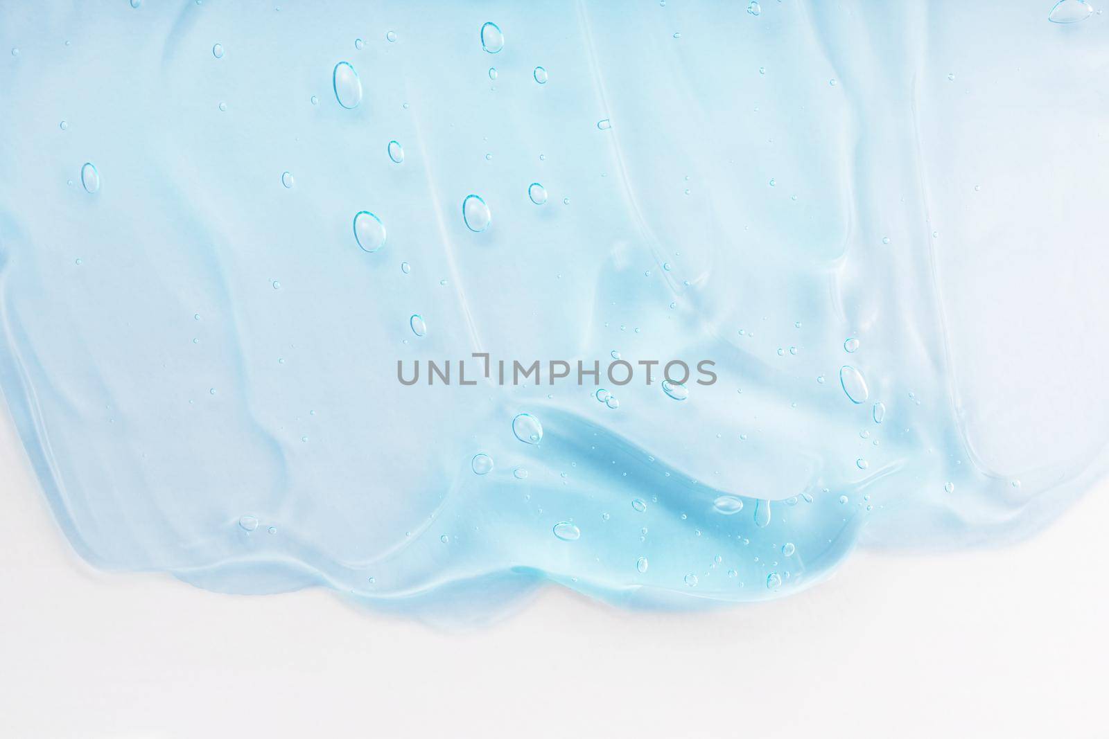 Clear skincare product smudge closeup. Cream gel blue transparent cosmetic sample with bubbles isolated on white background. Face serum texture. Hand sanitizer, hygiene liquid gel