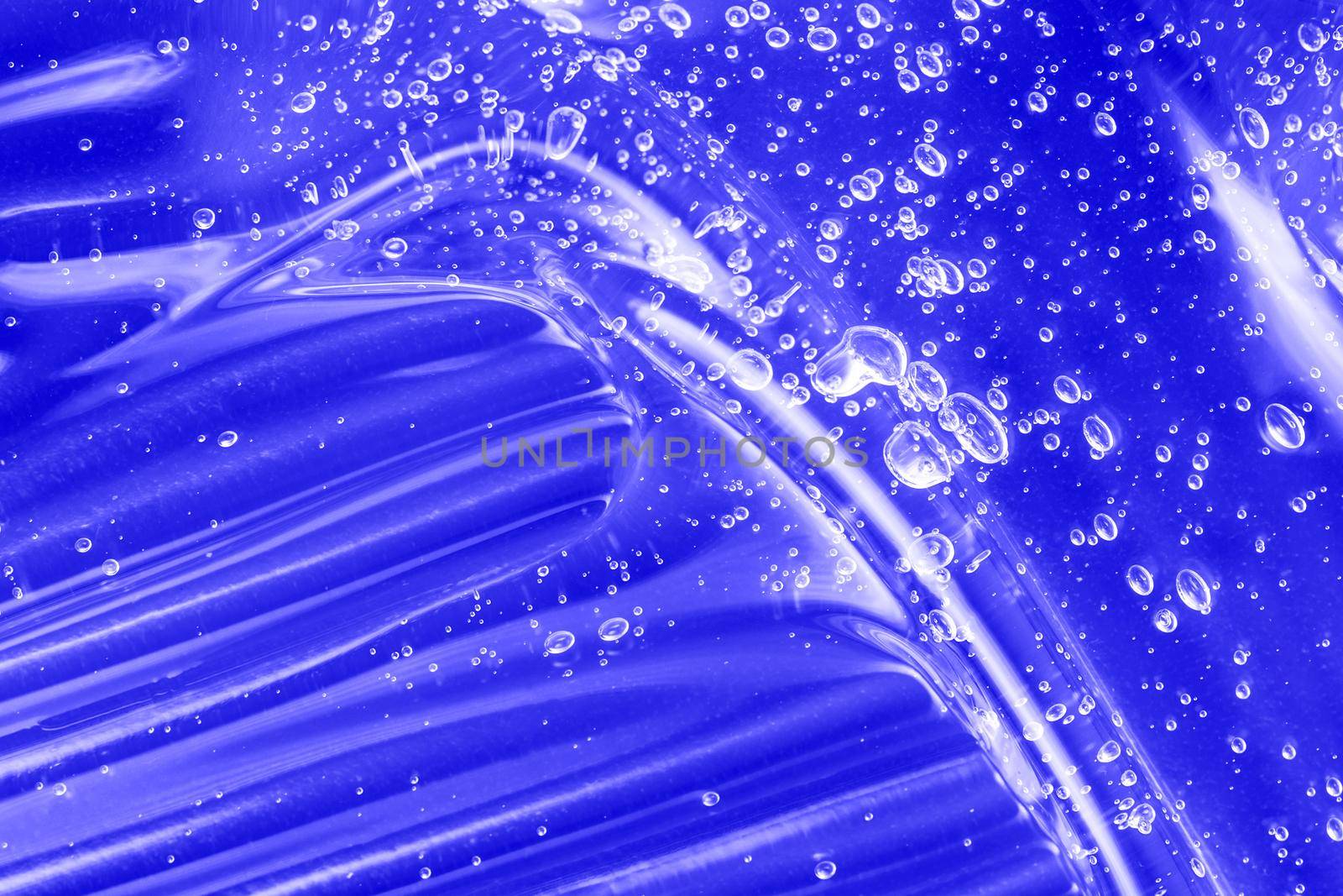 Liquid antibacterial disinfect smear smudge. Cosmetic blue gel texture with bubbles. Hyaluronic acid clear serum sample. Skincare moisturizing product background. Sanitizer swatch. Close-up, macro.
