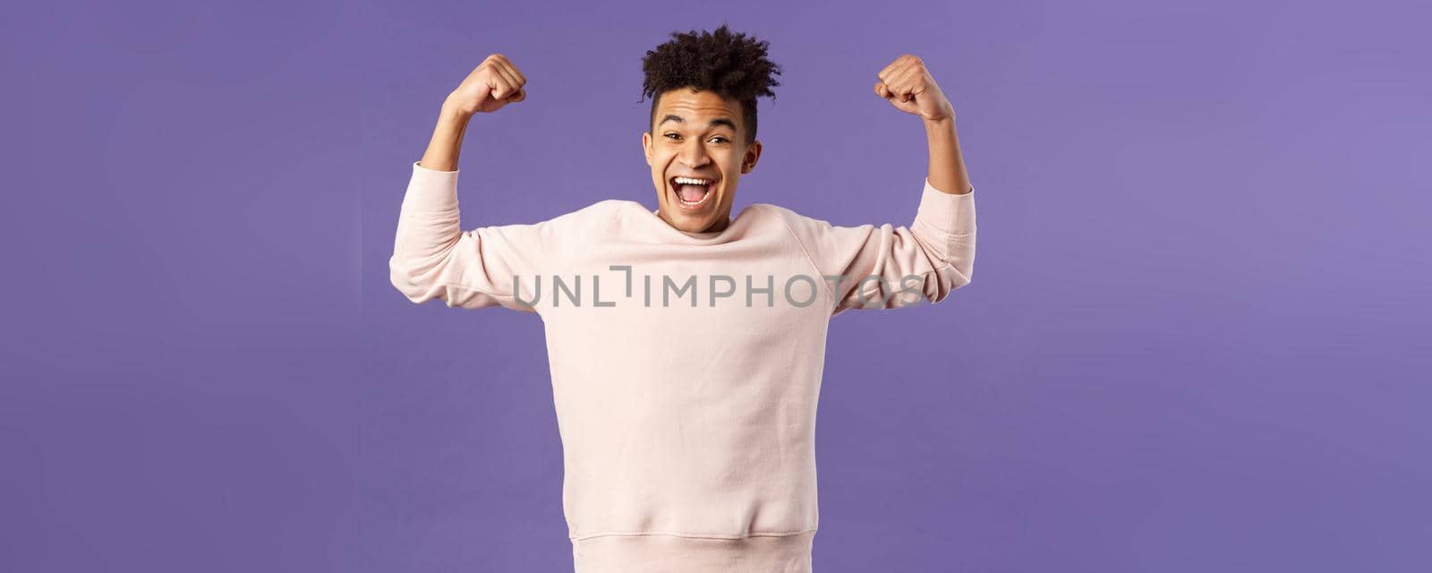 Portrait of young happy man got scholarship, applied to cool university, raise hands up flex biceps like champion, triumphing from great news, achieve goal and rejoicing, purple background by Benzoix