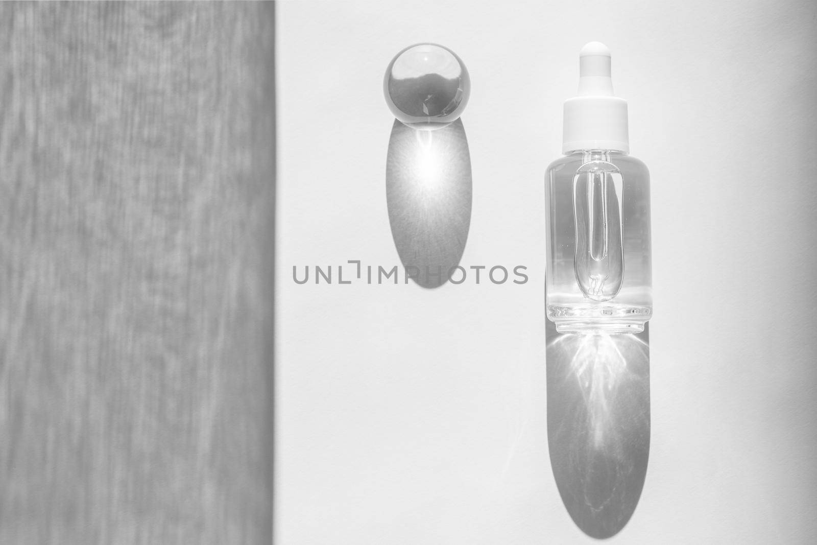 Transparent liquid product packaging in glass bottle. Hyaluronic acid oil mockup. Anti aging serum with collagen and peptides on white surface with sunlight and shadow. Flat lay, copy space by photolime