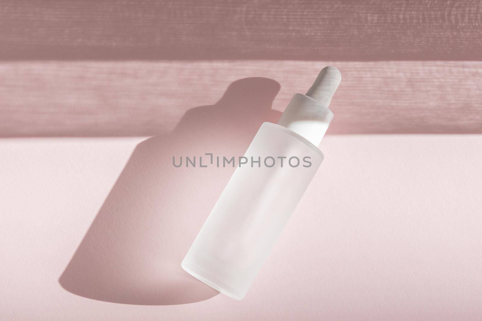 Skin moisturizing serum on pink backdrop with shadow. Beauty skincare essence mockup tincture flat lay, wellness packaging. Hyaluronic acid oil mock up. Lliquid product in glass bottle by photolime