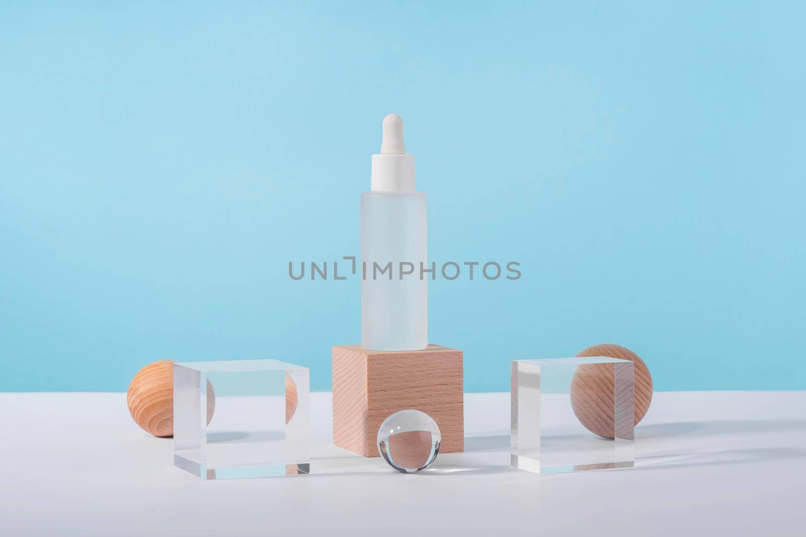 Oil cosmetics transparent product packaging with stylish props. Serum cosmetic bottle with peptides and retinol on acrylic and wooden blocks on blue background. Serum dropper mockup on pedestal by photolime