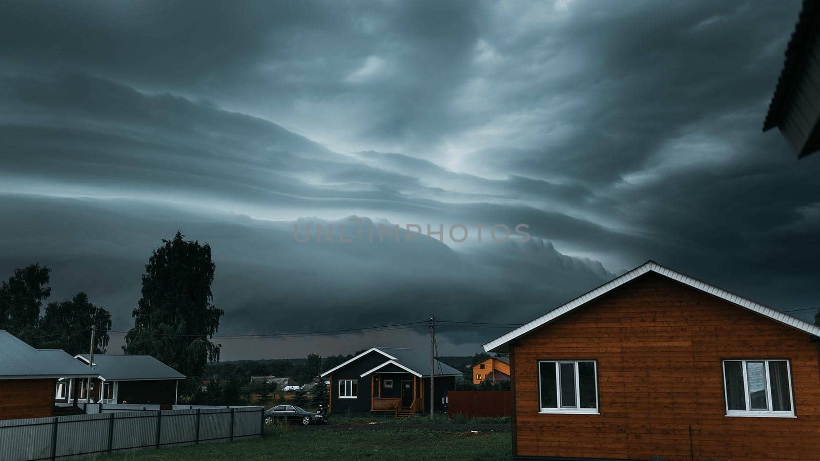 Thunderbolt over the house in the village and dark stormy sky on the background by Hitachin