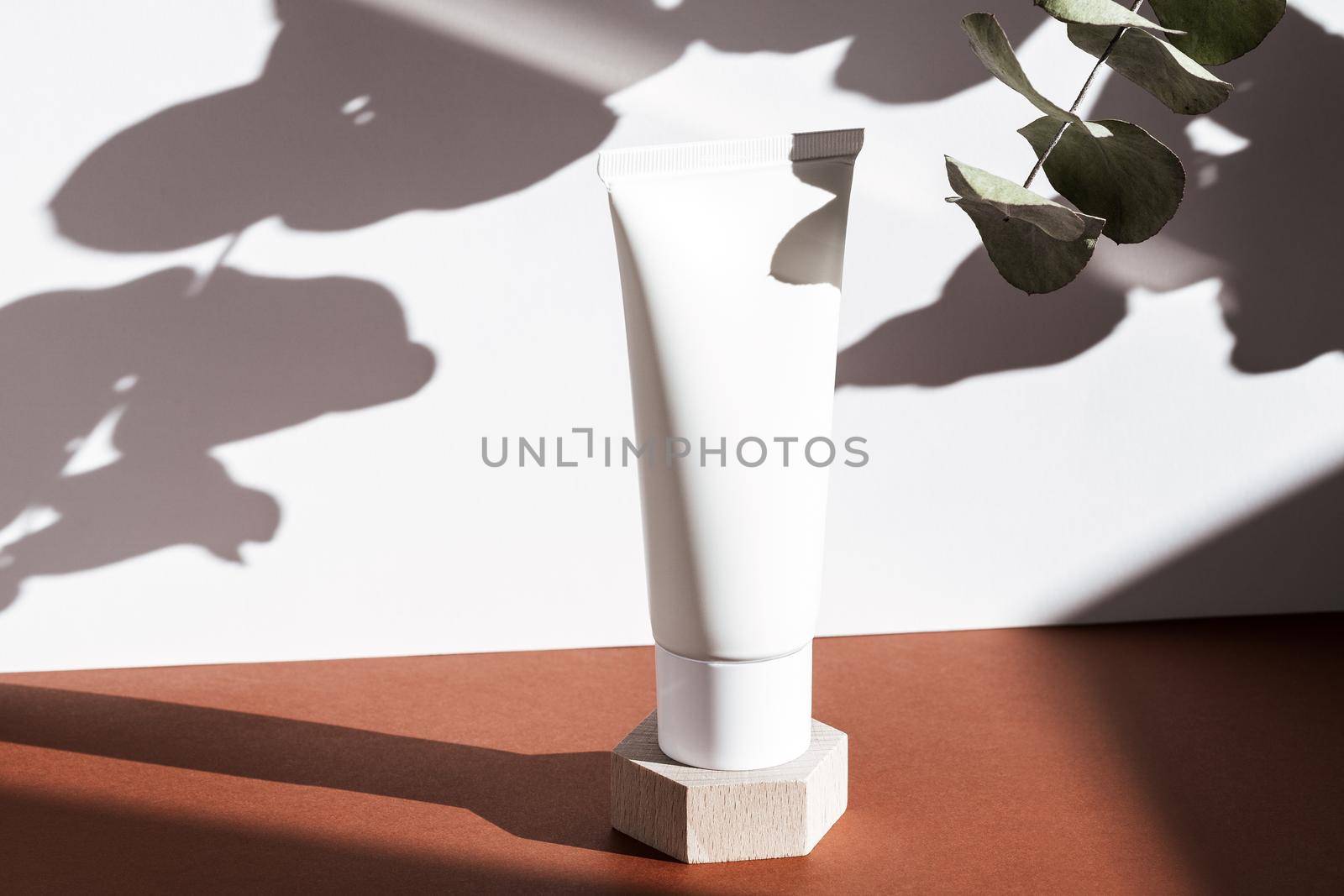 White cosmetic cream tube on wooden geometric pedestal podium, product packaging with natural shadows from plants, body scrub, moisturizing clear, shampoo mockup, biophilic concept. by photolime