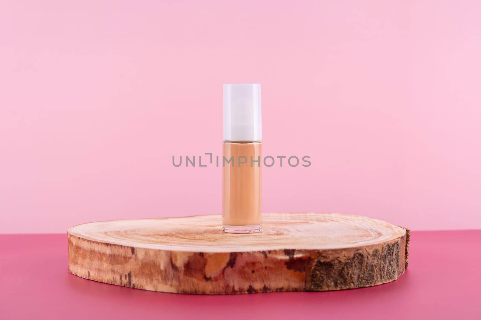 Cosmetic liquid foundation nude cream bottle mockup on wooden podium. Beige concealer base cosmetics product mock up on pink background. Skincare beauty primer, bb corrector