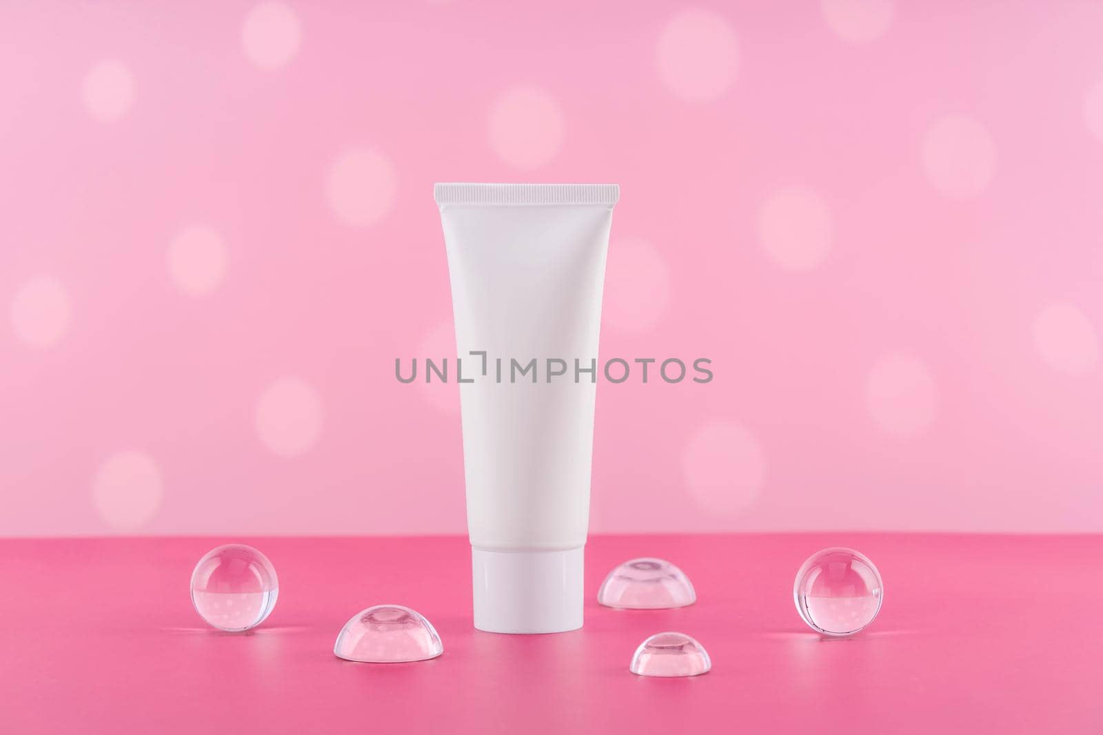 Unbranded cosmetic cream white plastic tube mockup on pink background. Blank body and health care beauty product packaging. Moisturising hand creme bottle with stylish props. Product presentation