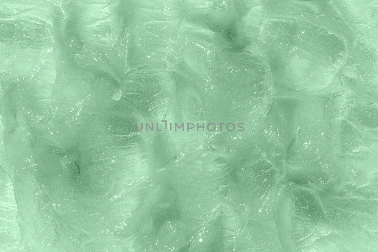 Liquid green balm texture smudge. The concept of natural cosmetics. Homemade beeswax sample. Aloe vera cosmetic gel texture background. Skincare moisturizing product. Close-up, macro.