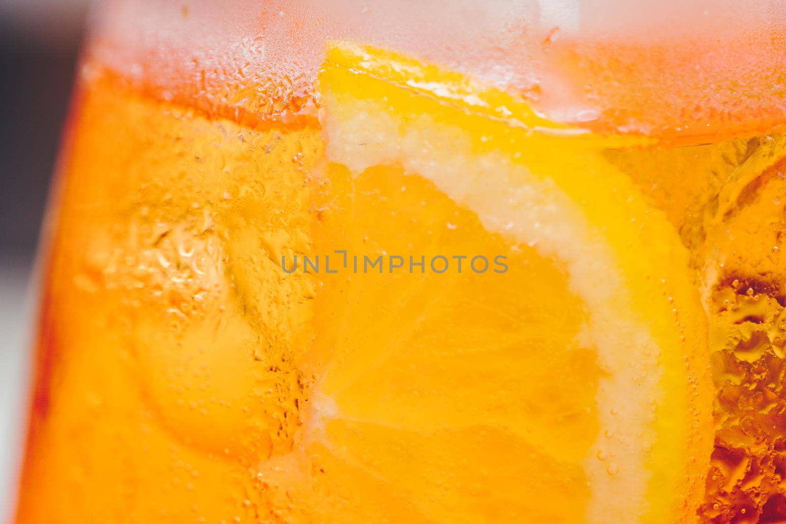 Glass of ice cold Aperol spritz cocktail served in a wine glass, decorated with slices of orange. Aperitif in street caffe in Italy. Macro by photolime