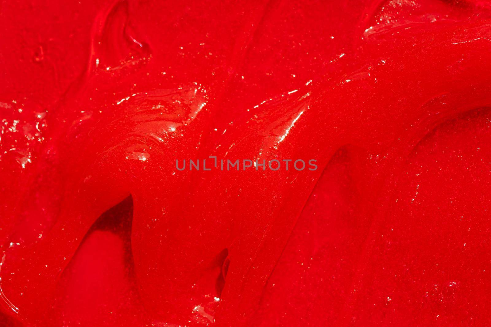 Red gel texture. Cosmetic clear liquid cream smudge. Skin care product sample closeup. Toothpaste or wax background