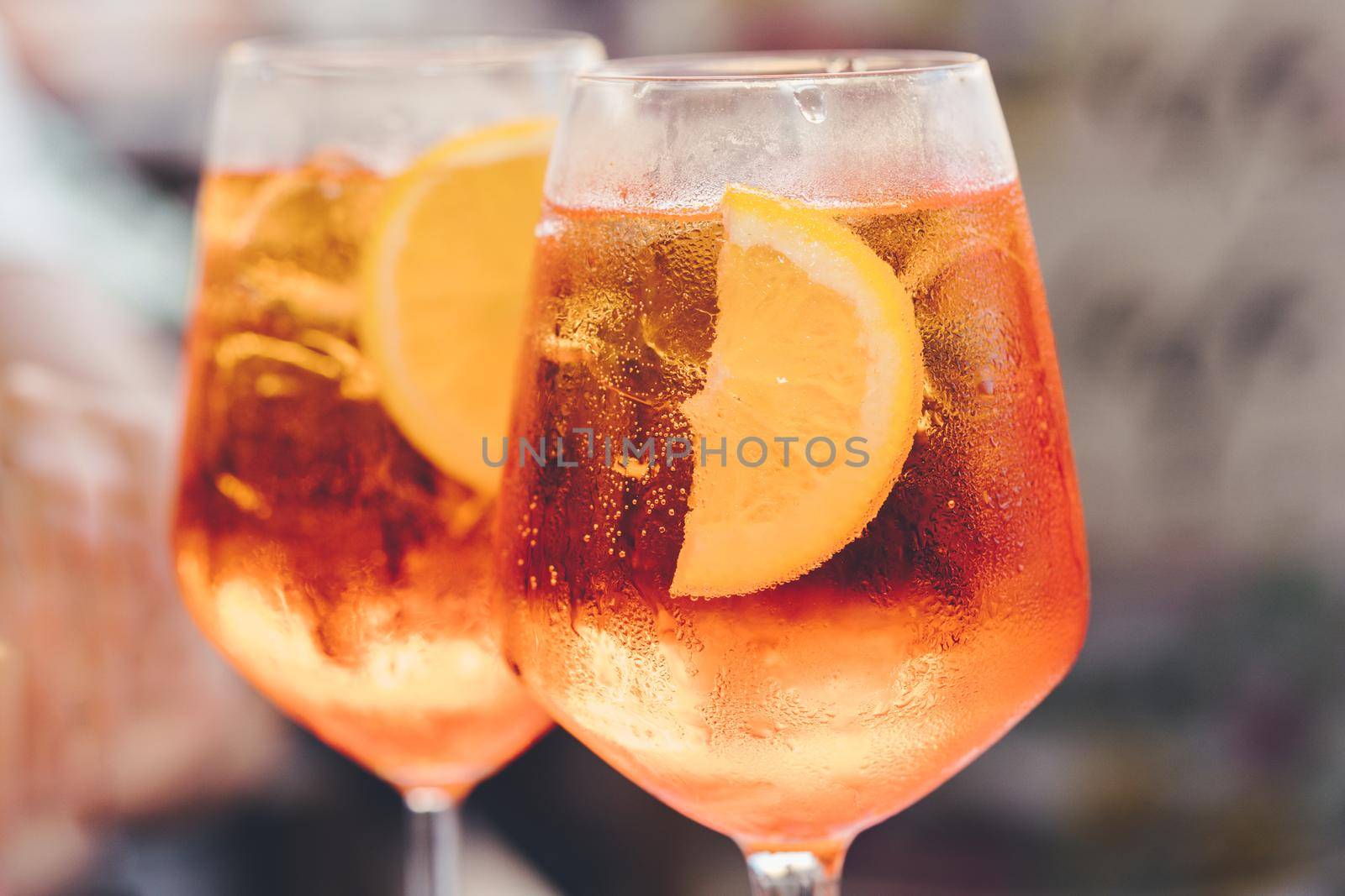 Glass of ice cold Aperol spritz cocktail served in a wine glass, decorated with slices of orange. Aperitif in street caffe in Italy