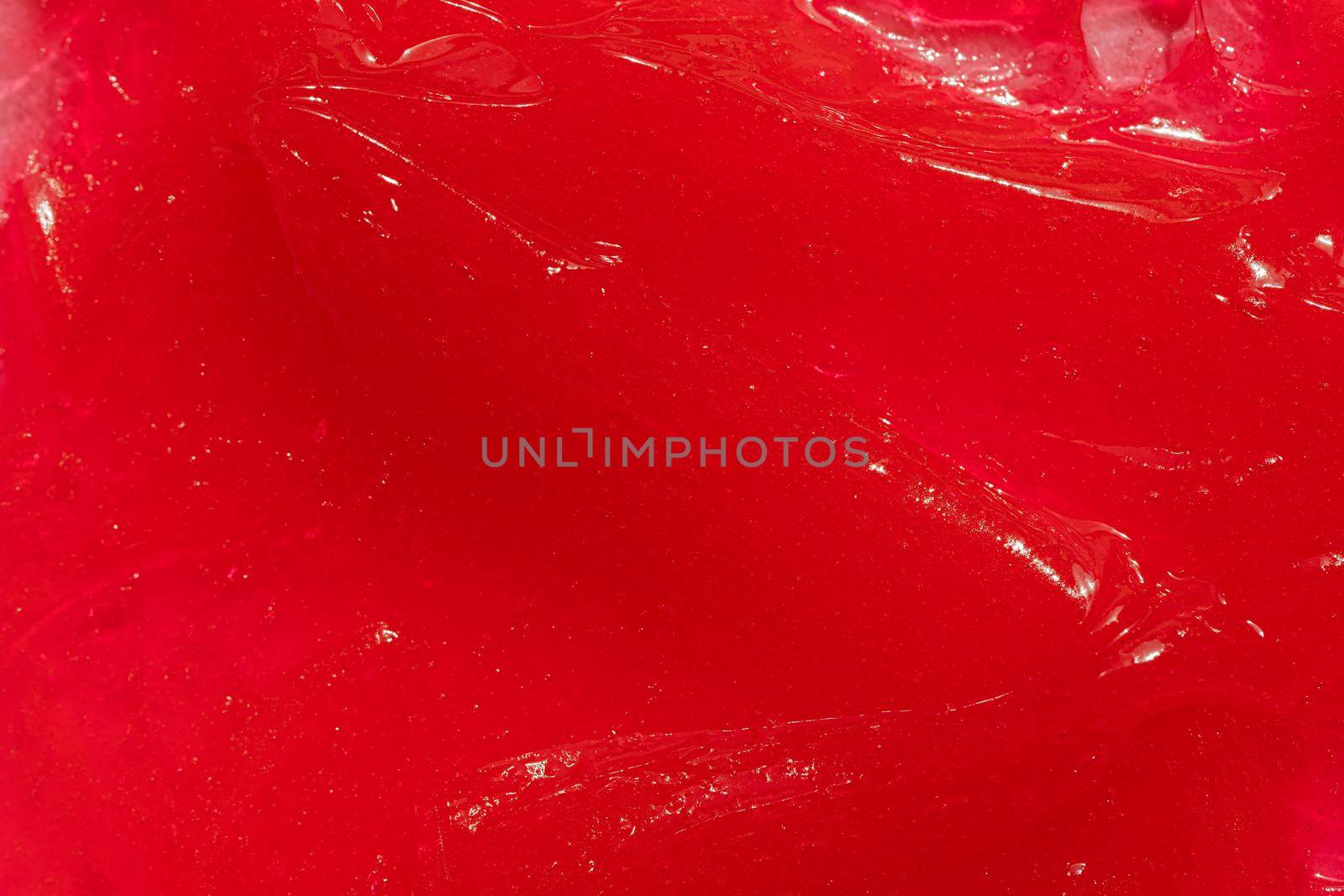 Red gel texture. Cosmetic clear liquid cream smudge. Skin care product sample closeup. Toothpaste or wax background