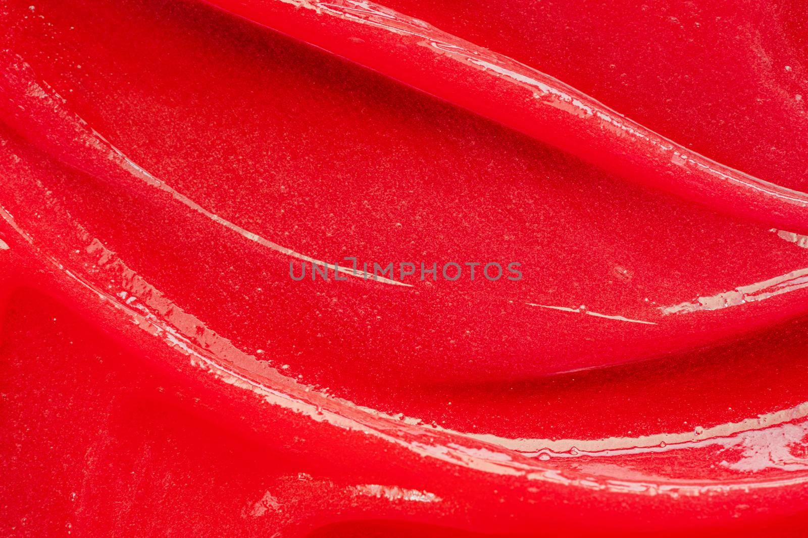 Red gel texture. Cosmetic clear liquid cream smudge. Skin care product sample closeup. Toothpaste or wax background