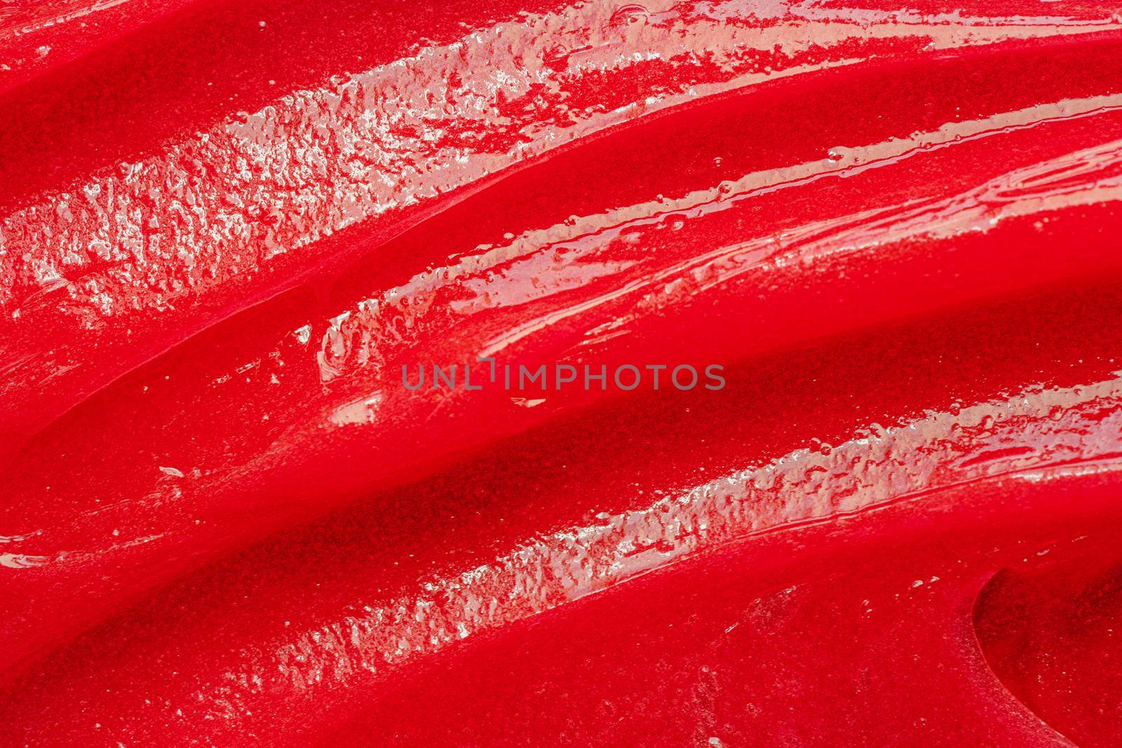 Red gel texture. Cosmetic clear liquid cream smudge. Skin care product sample closeup. Toothpaste or wax background