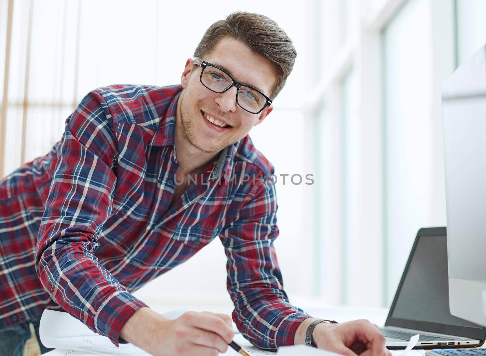 Back view of businessman sitting in front of laptop screen. Man typing on a modern laptop in an office. Young student typing on computer sitting at wooden table. by Prosto