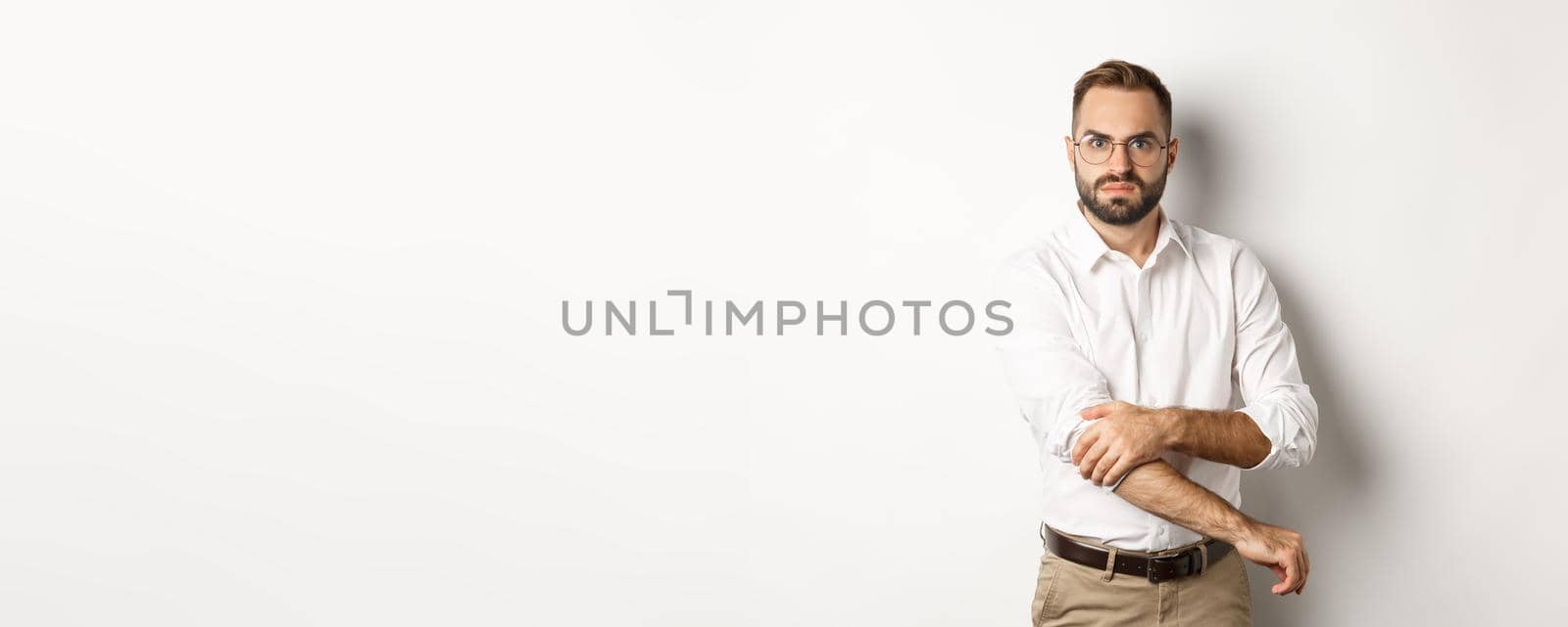 Angry man roll up sleeves and looking offended, getting ready to fight, standing over white background by Benzoix