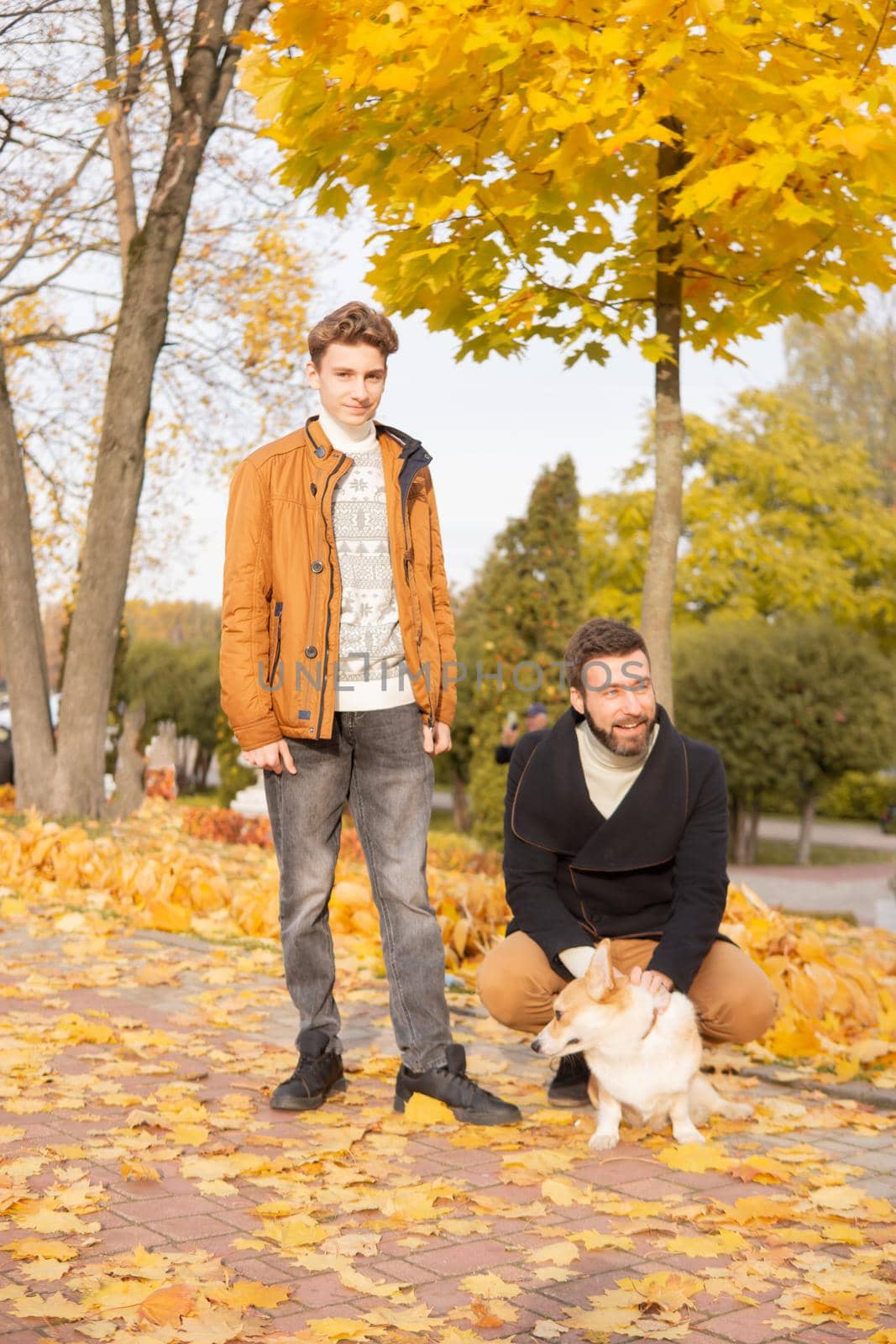 Father and son with a pet on a walk in the autumn park.