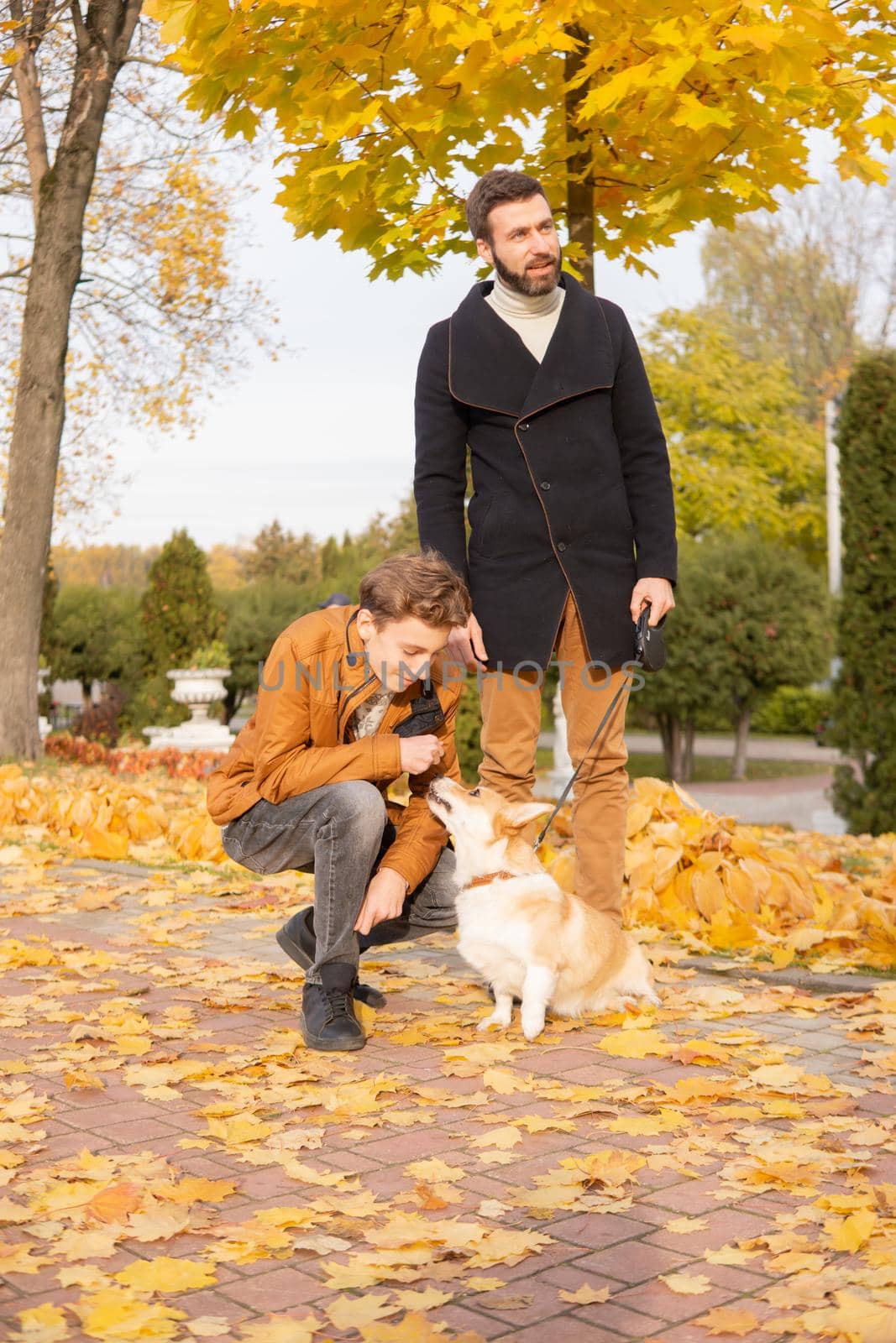 Father and son with a pet on a walk in the autumn park.