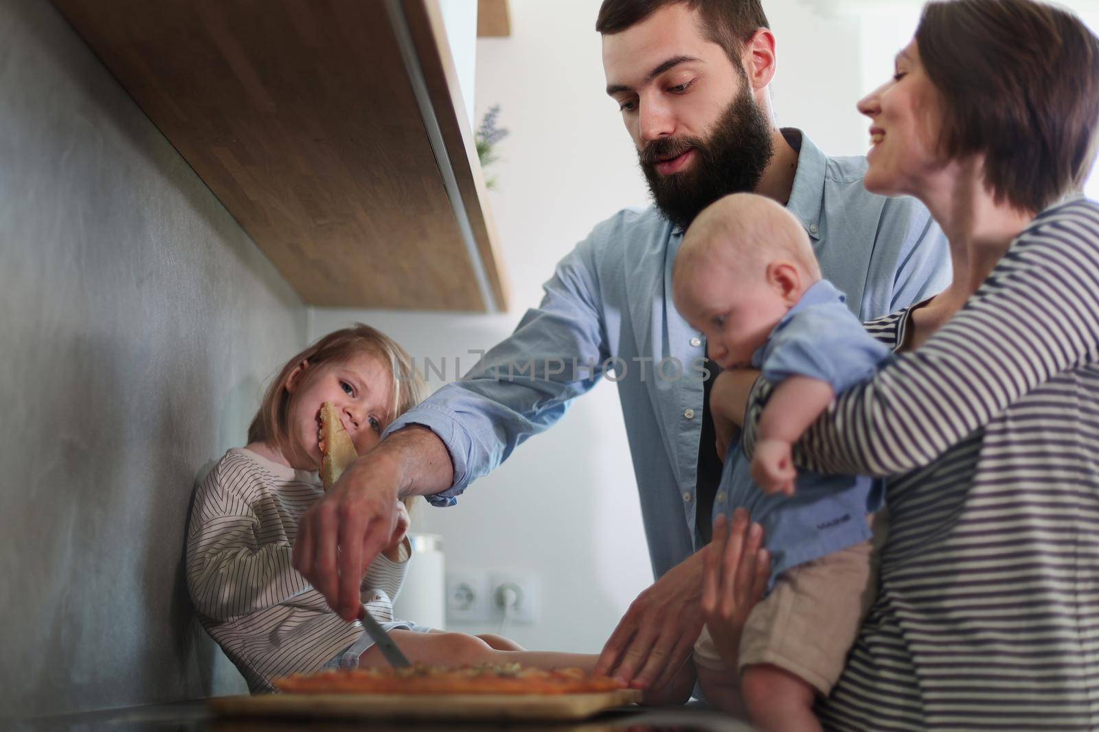 Family of 4 posing in the kitchen smiling and happy by Prosto