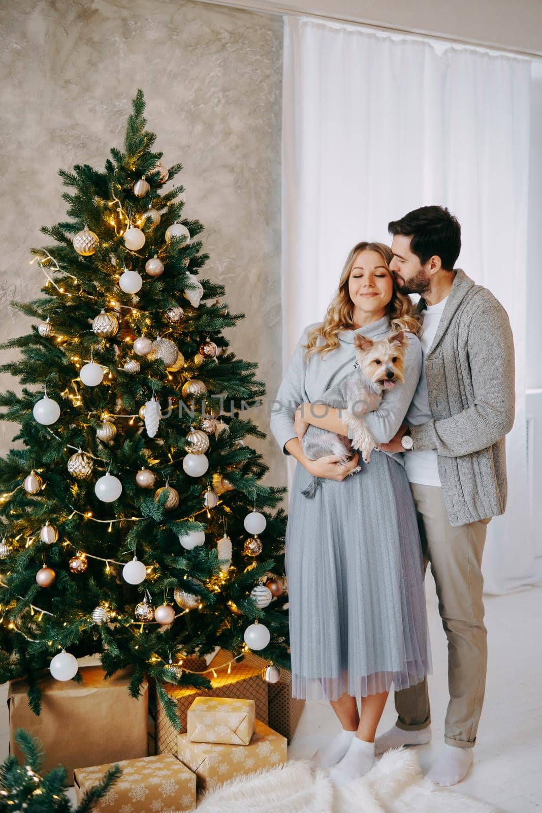 A happy couple in love - a man and a woman. A family in a bright New Year's interior with a Christmas tree by Annu1tochka