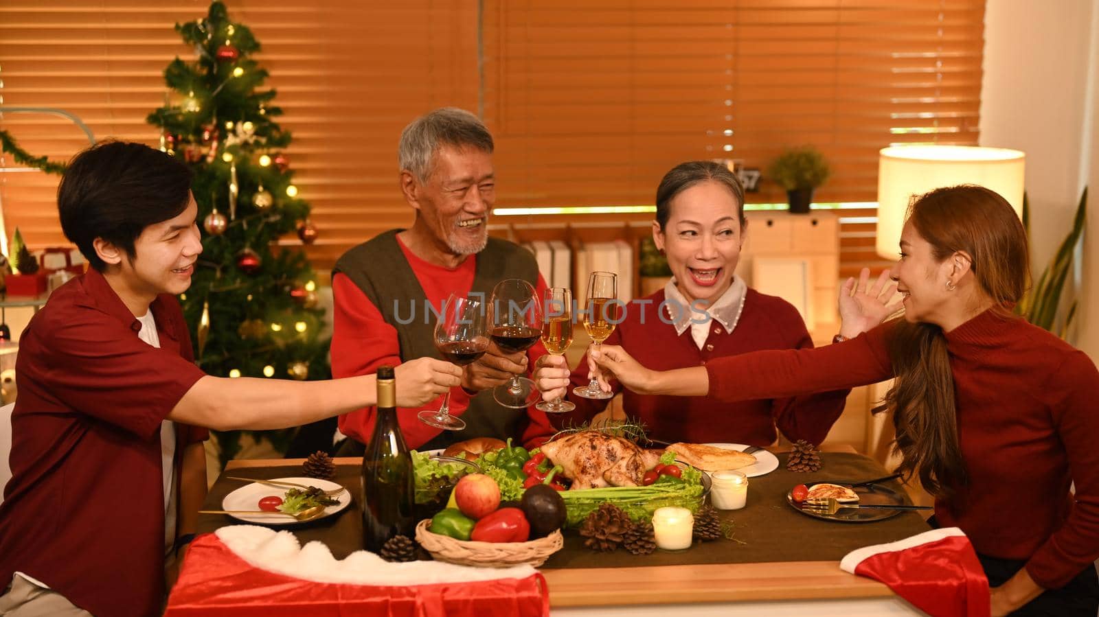 Happy family are clinking glass of wine during celebrating Christmas party dinner. Christmas and thanksgiving concept by prathanchorruangsak
