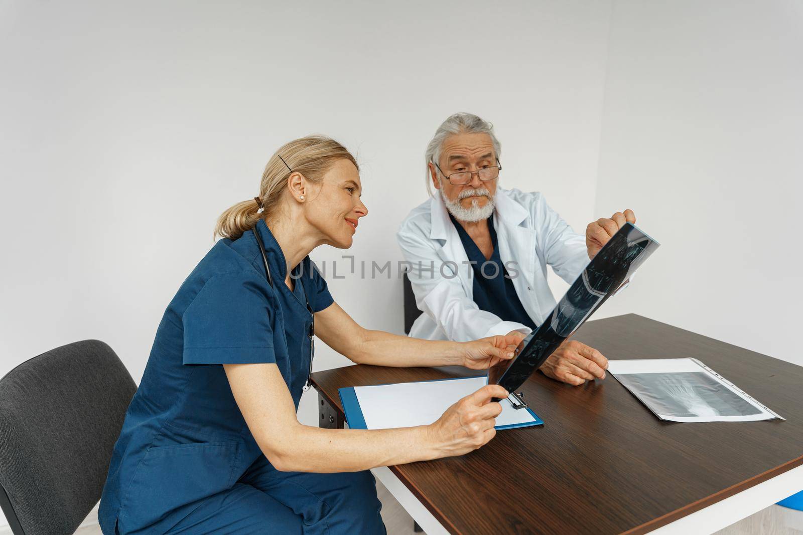 Team of doctors looking on results of X-Ray or MRI scan of patient's spine in medicine office