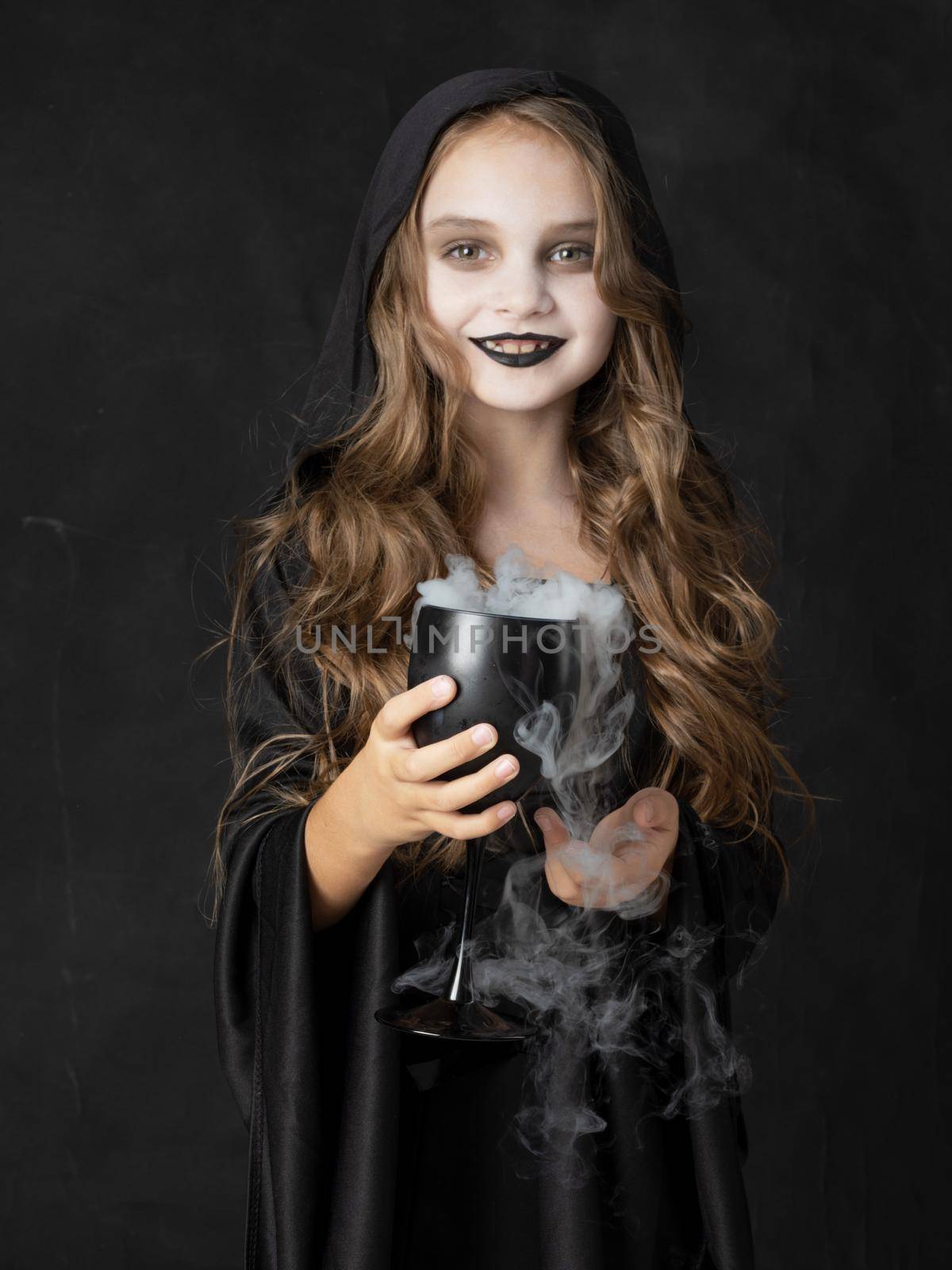 Little Halloween witch with smoke potion in goblet