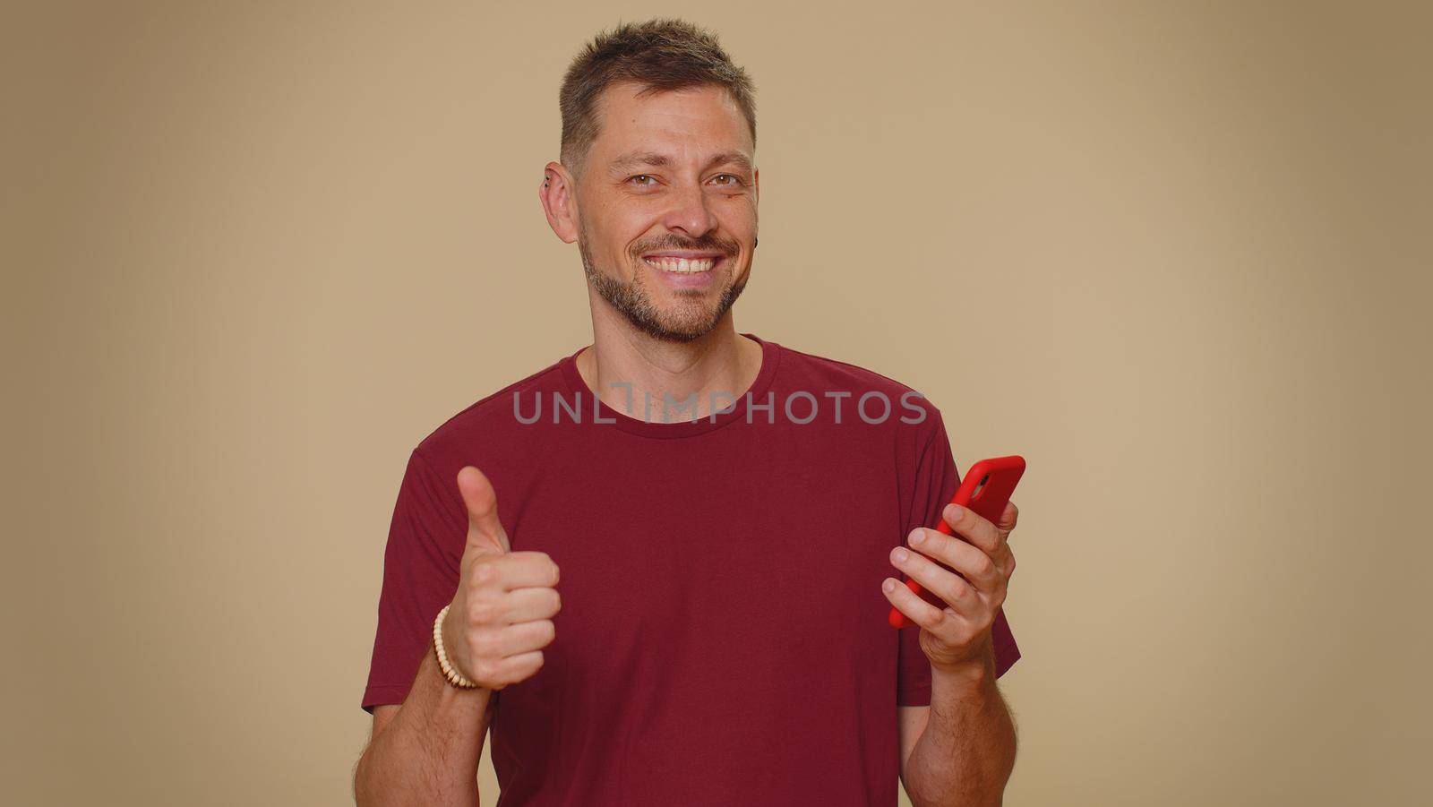 Handsome young male man using smartphone typing new post on web, browsing, searching, addiction of social networks, show thumbs up like, positive feedback, recommends wifi cellular connection 5G