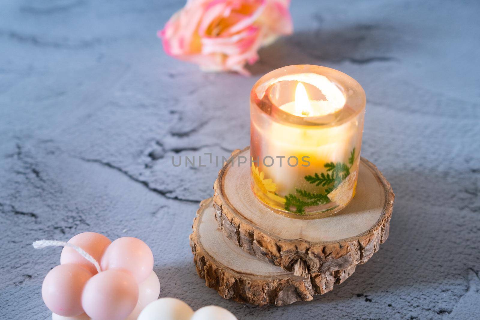 Lit resin art transparent candle on wood coaster with flowers showing the decoration of diwali, christmas, new year shot in pastel shades