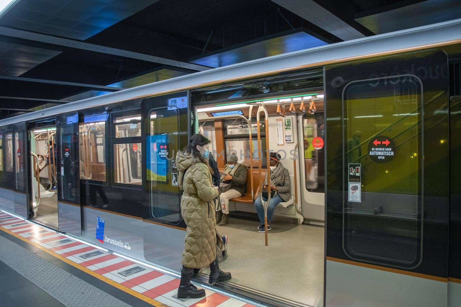 Brussels, Belgium - 01.31.2022 A young woman enters a subway car in a big city on a platform while masked people sit there. High quality photo