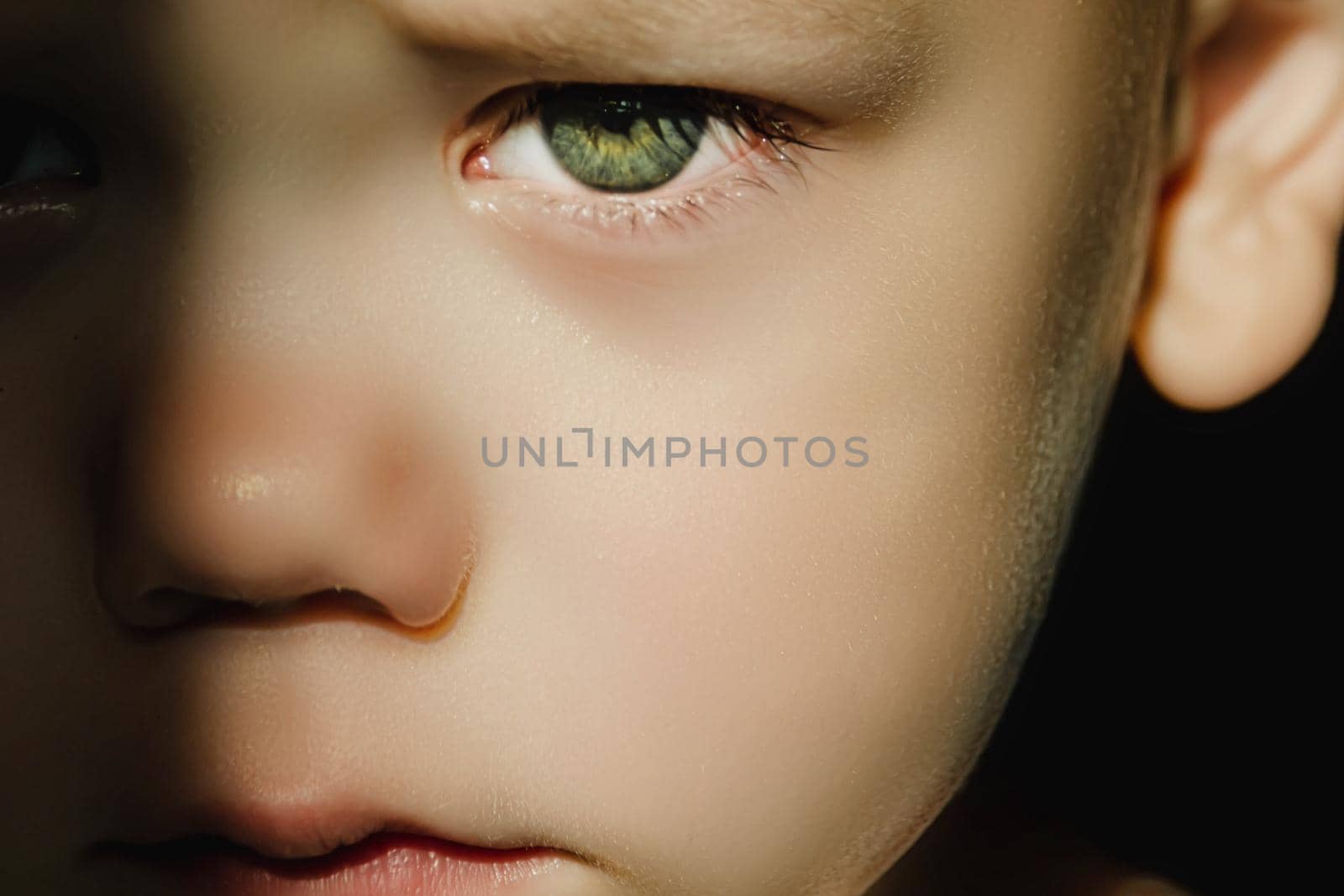 Expressive look of a small child. Baby's eye close-up. Gray green iris