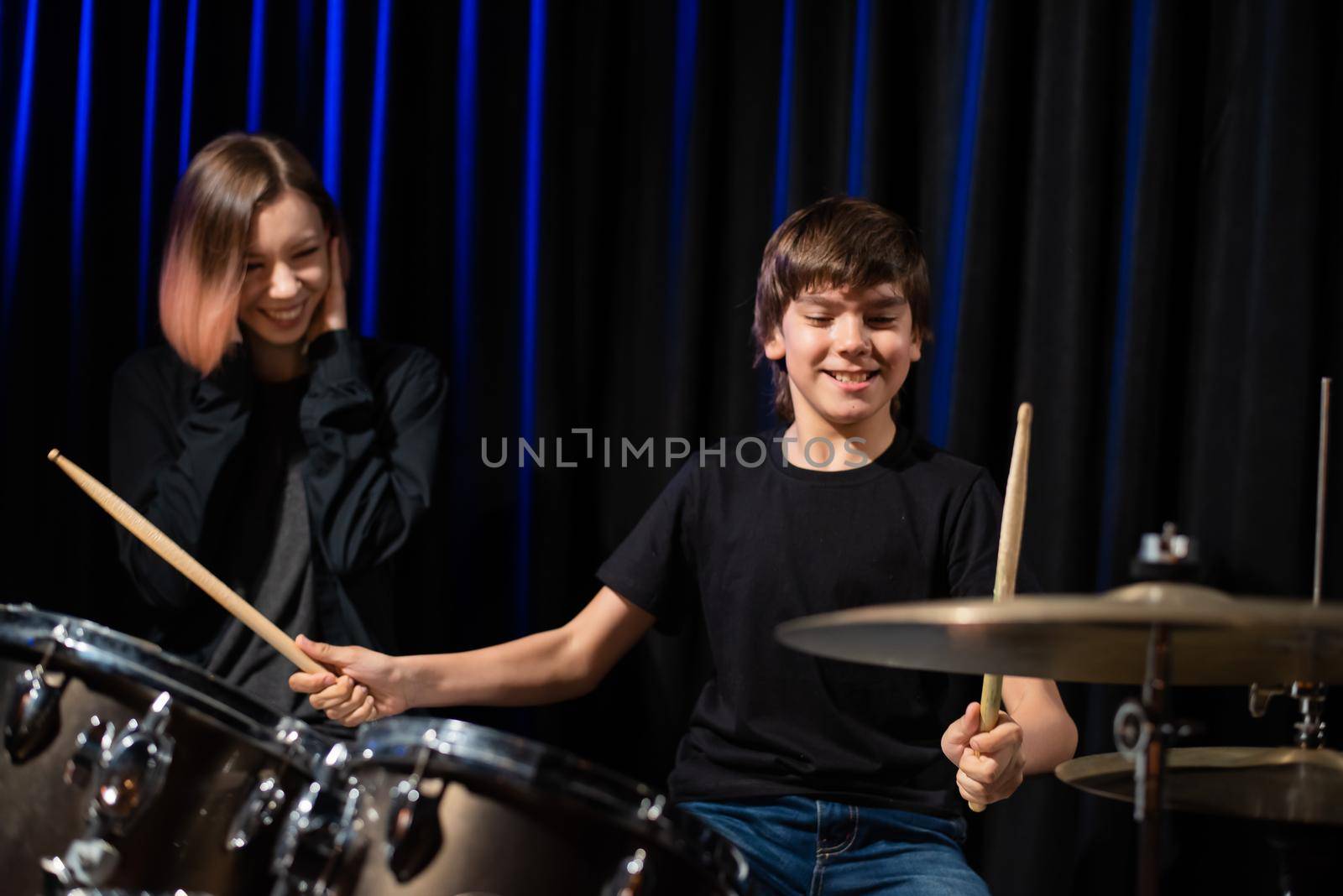 Young woman teaching boy to play drums