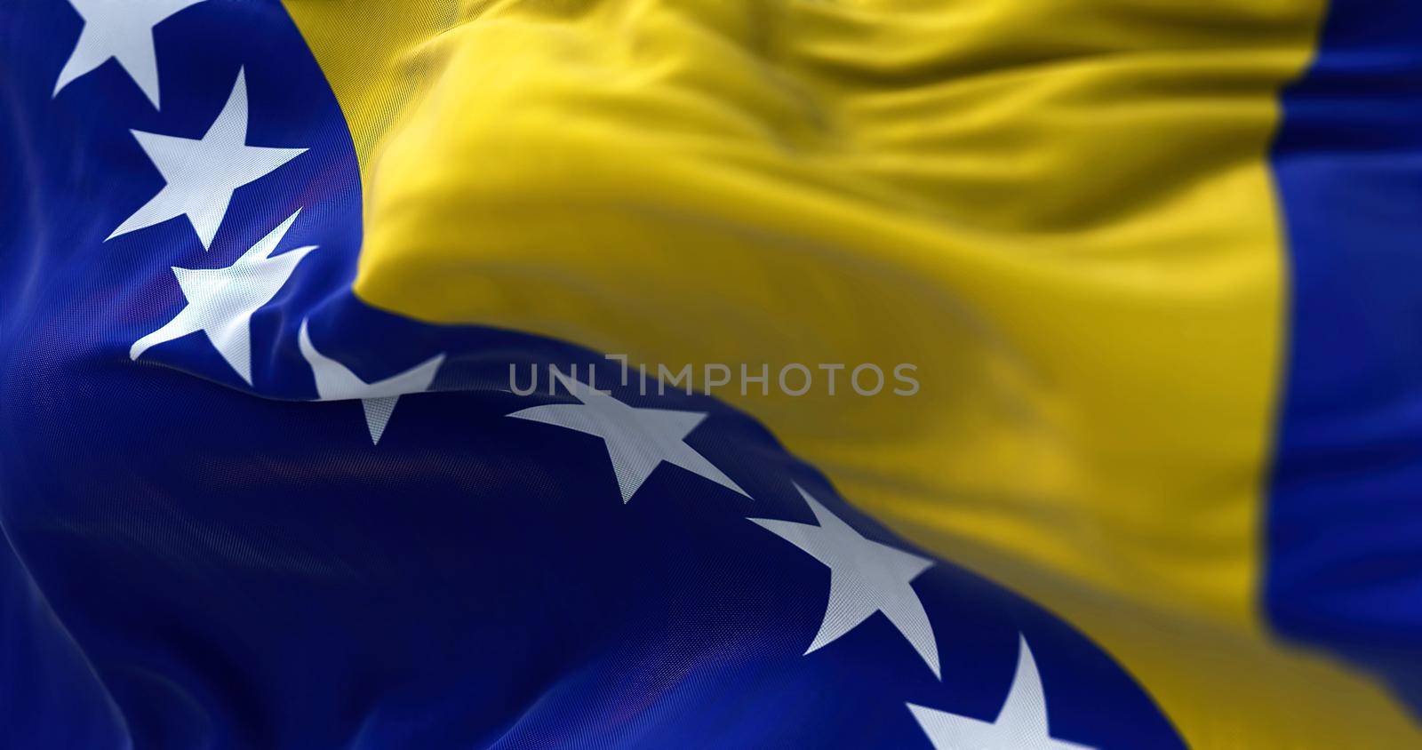 Close-up view of the bosnian national flag waving in the wind. Bosnia and Herzegovina is a country at the crossroads of south and southeast Europe. Fabric textured background. Selective focus