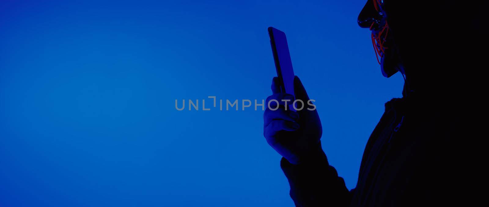 Digital security Concept. Anonymous hacker with mask holding smartphone hacked. by gnepphoto