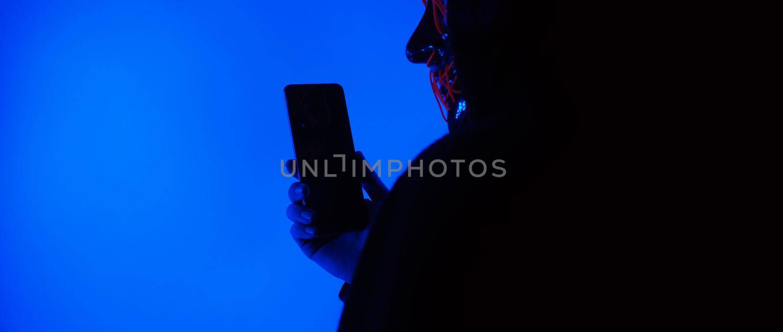 Digital security Concept. Anonymous hacker with mask holding smartphone hacked. by gnepphoto