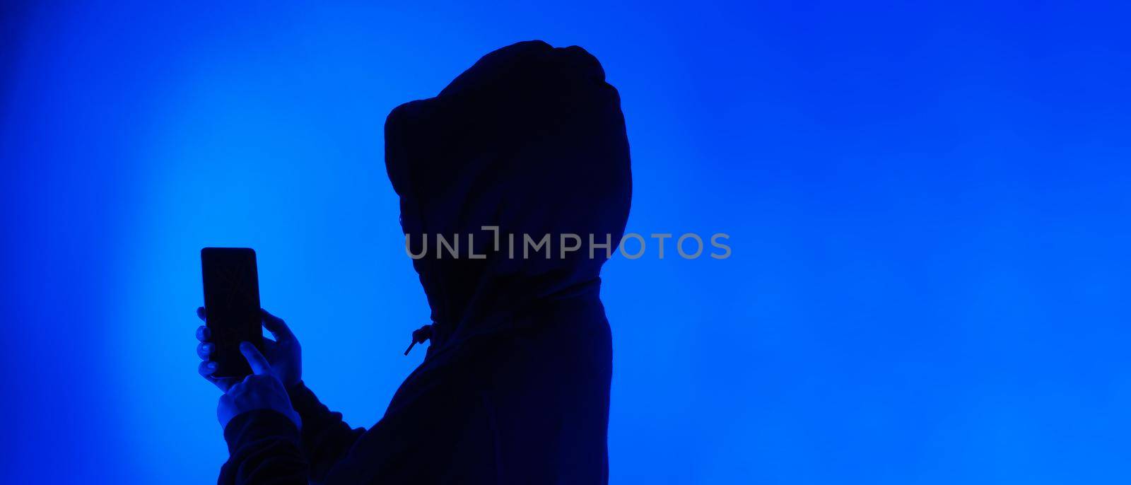 Digital security Concept. Anonymous hacker with mask holding smartphone hacked. by gnepphoto