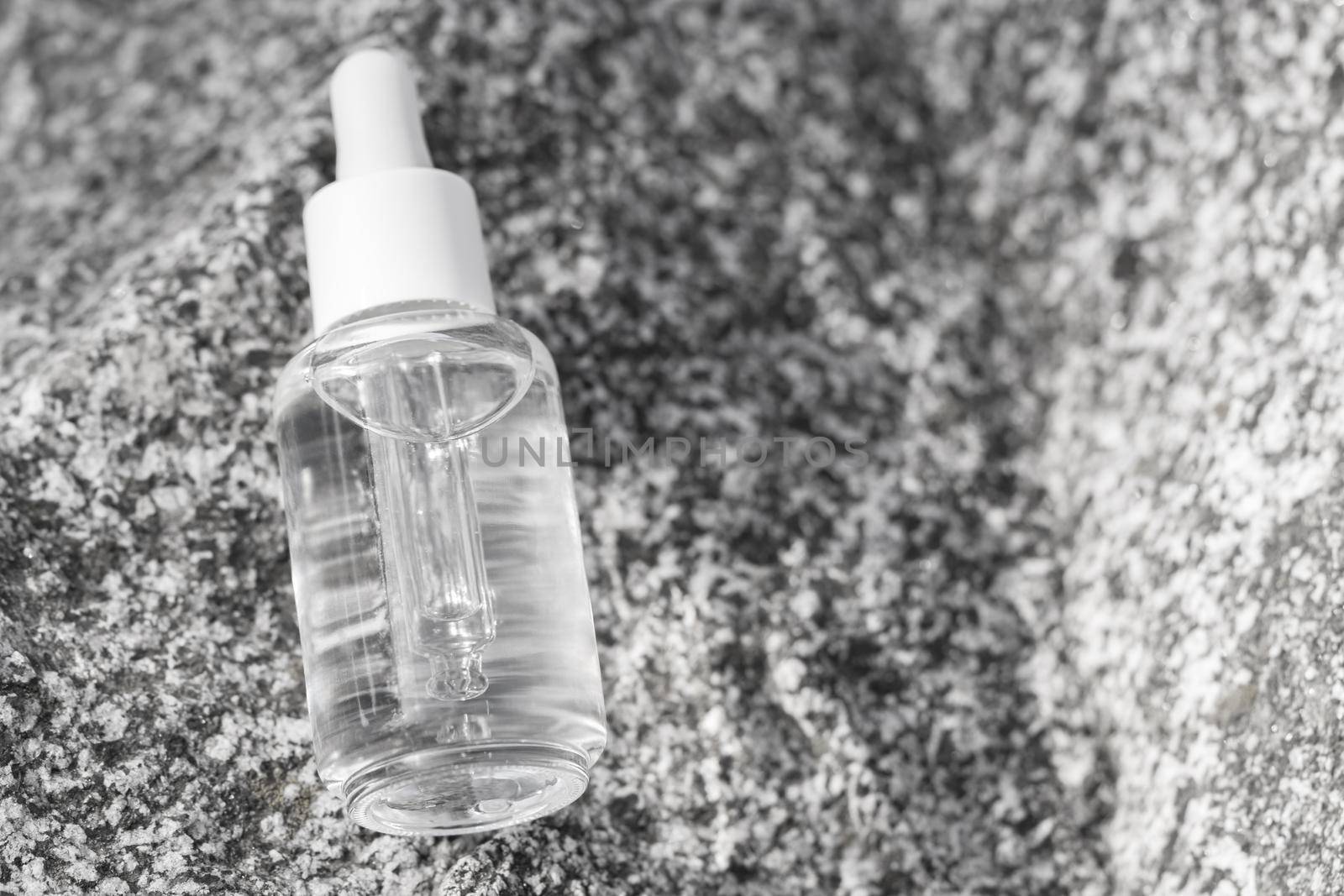 Serum glass transparent bottle with pipette on stone surface. Natural organic spa cosmetic concept. by photolime