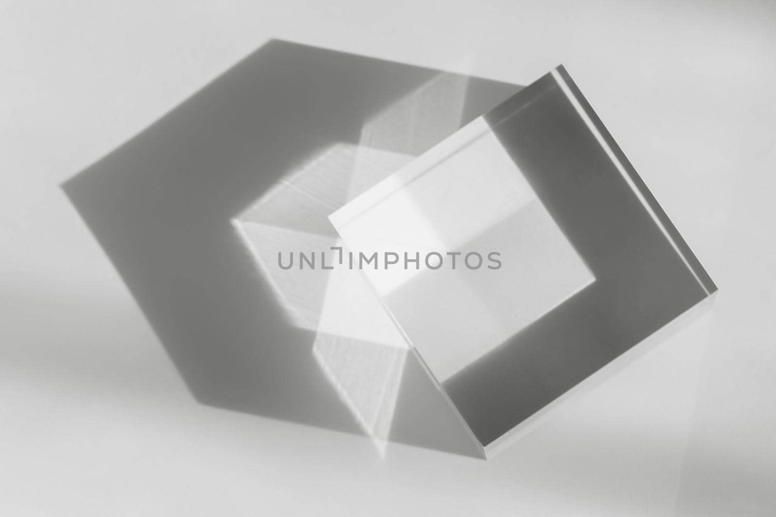 Glass transparent cube with sun reflection, light and shadow on white background. Physics refraction effect, translucent prism. Decor for flat lay with cosmetic display, abstract background. by photolime