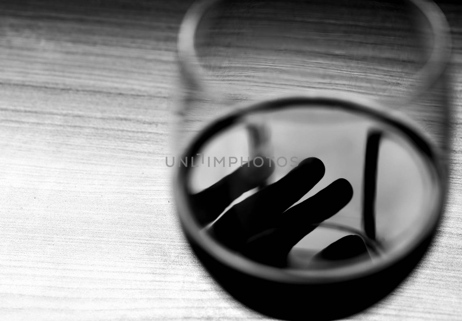 Glass of red wine and dark hand silhouette on it by soniabonet