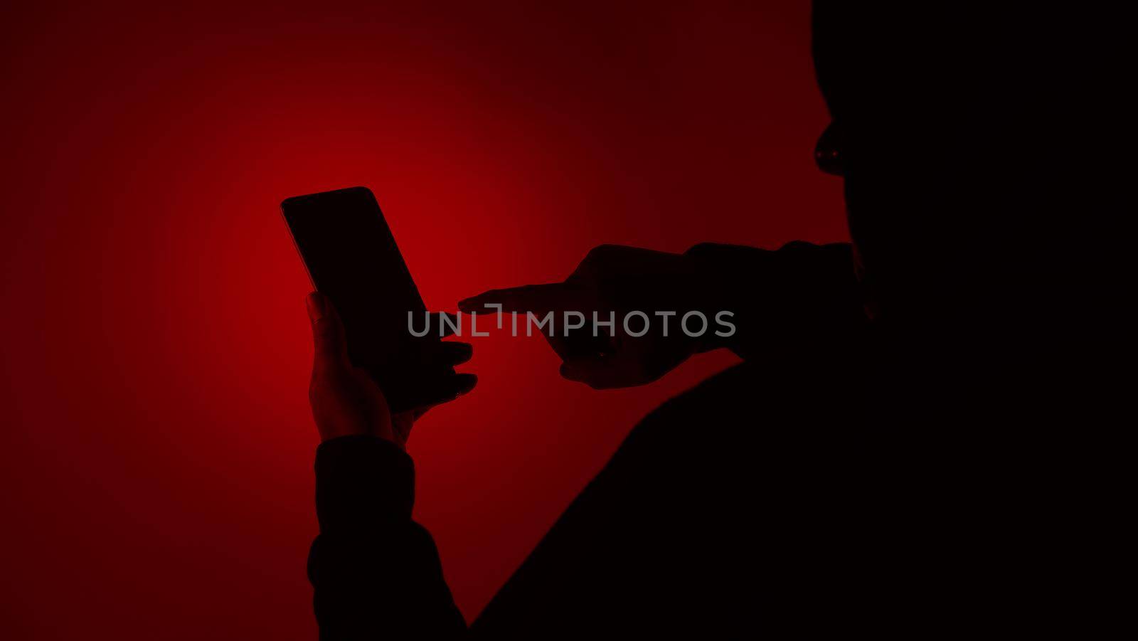 Digital security Concept. Anonymous hacker with mask holding smartphone hacked. Personal and Cyber data security in mobile phone stolen by man in mask. Represent digital privacy protection concept.