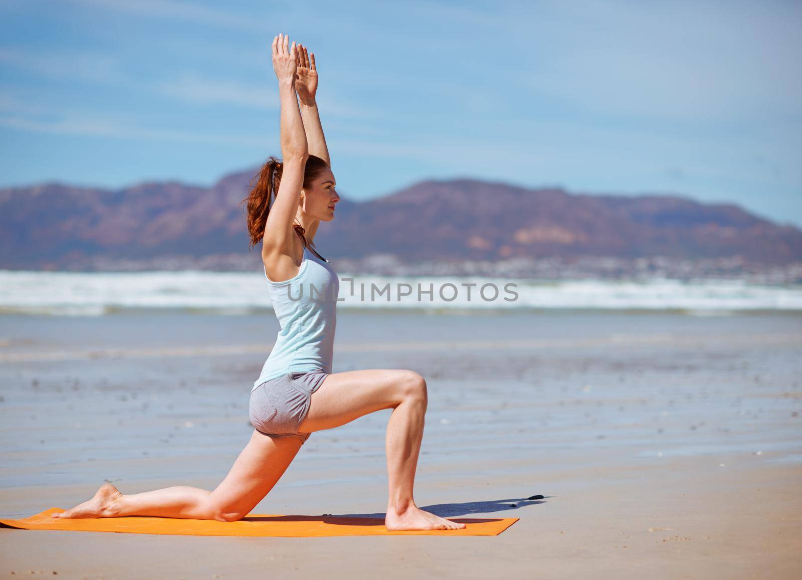 Keep calm and yoga on. a young woman practicing her yoga routine at the beach. by YuriArcurs
