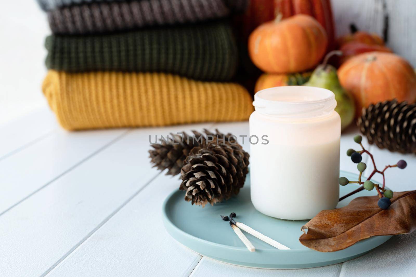 Hello fall. Cozy warm image. High angle view autumn composition with sweaters and candles, white candle mockup design