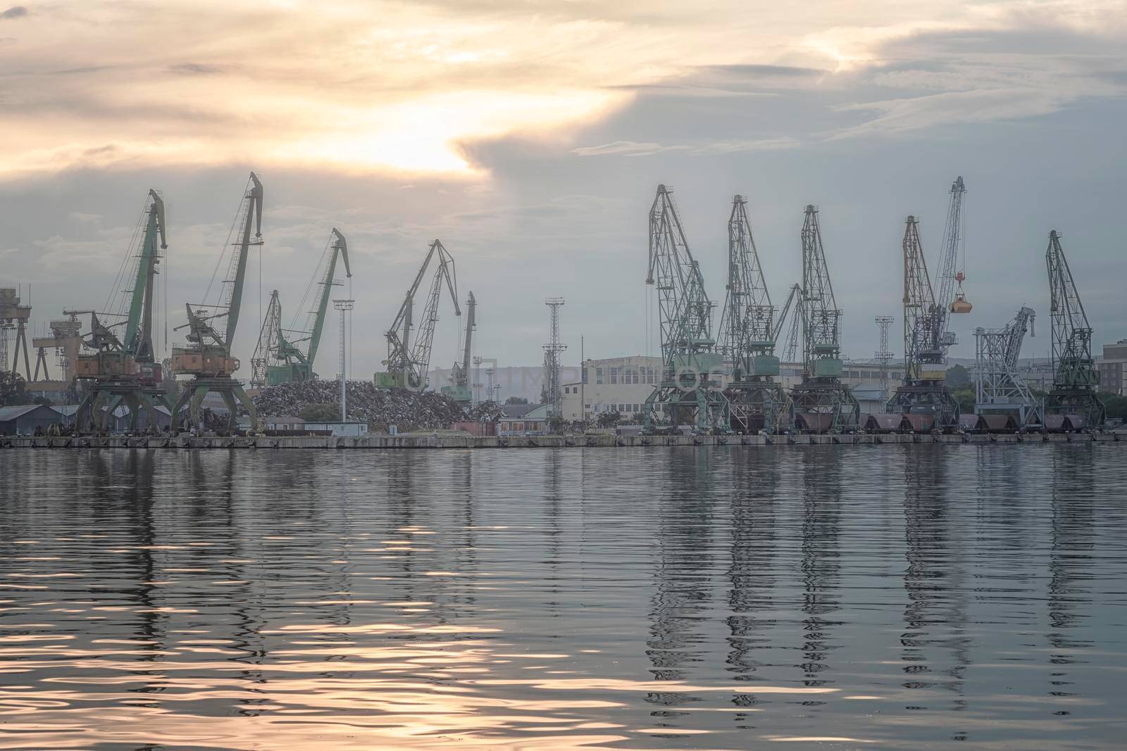 In the evening, the silhouette of port cranes. Ready to load containers from cargo ships.