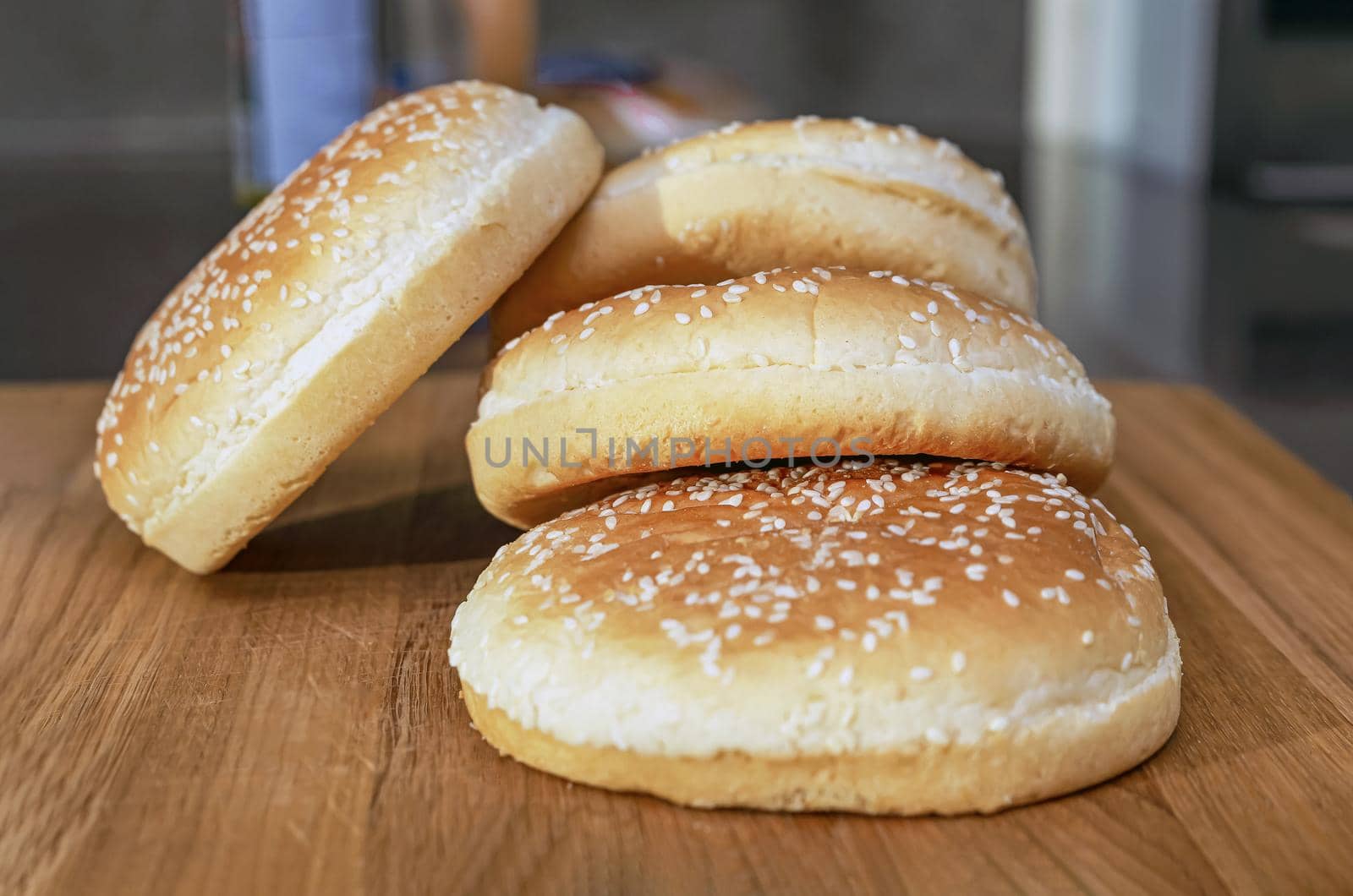 frozen buns for a burger lie in a stack on a wooden cutting board, the process of preparing a burger in the kitchen at home