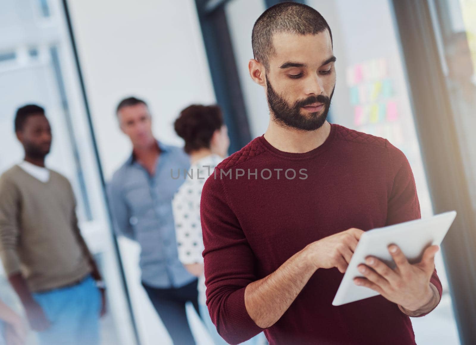 Hes got business on the brain. a young businessman working in the office with her colleagues in the background. by YuriArcurs