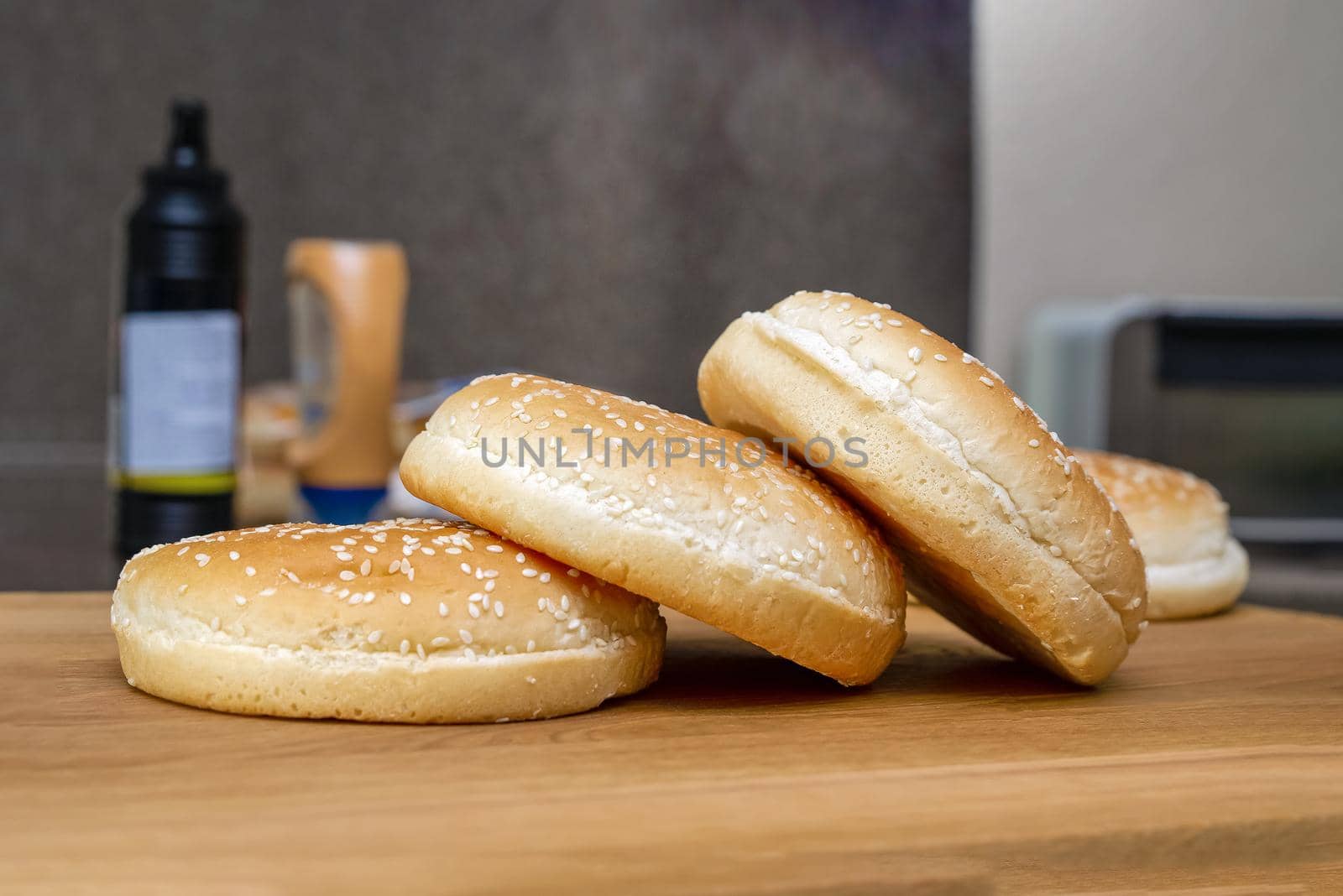 frozen buns for a burger lie in a stack on a wooden cutting board, the process of preparing a burger in the kitchen at home