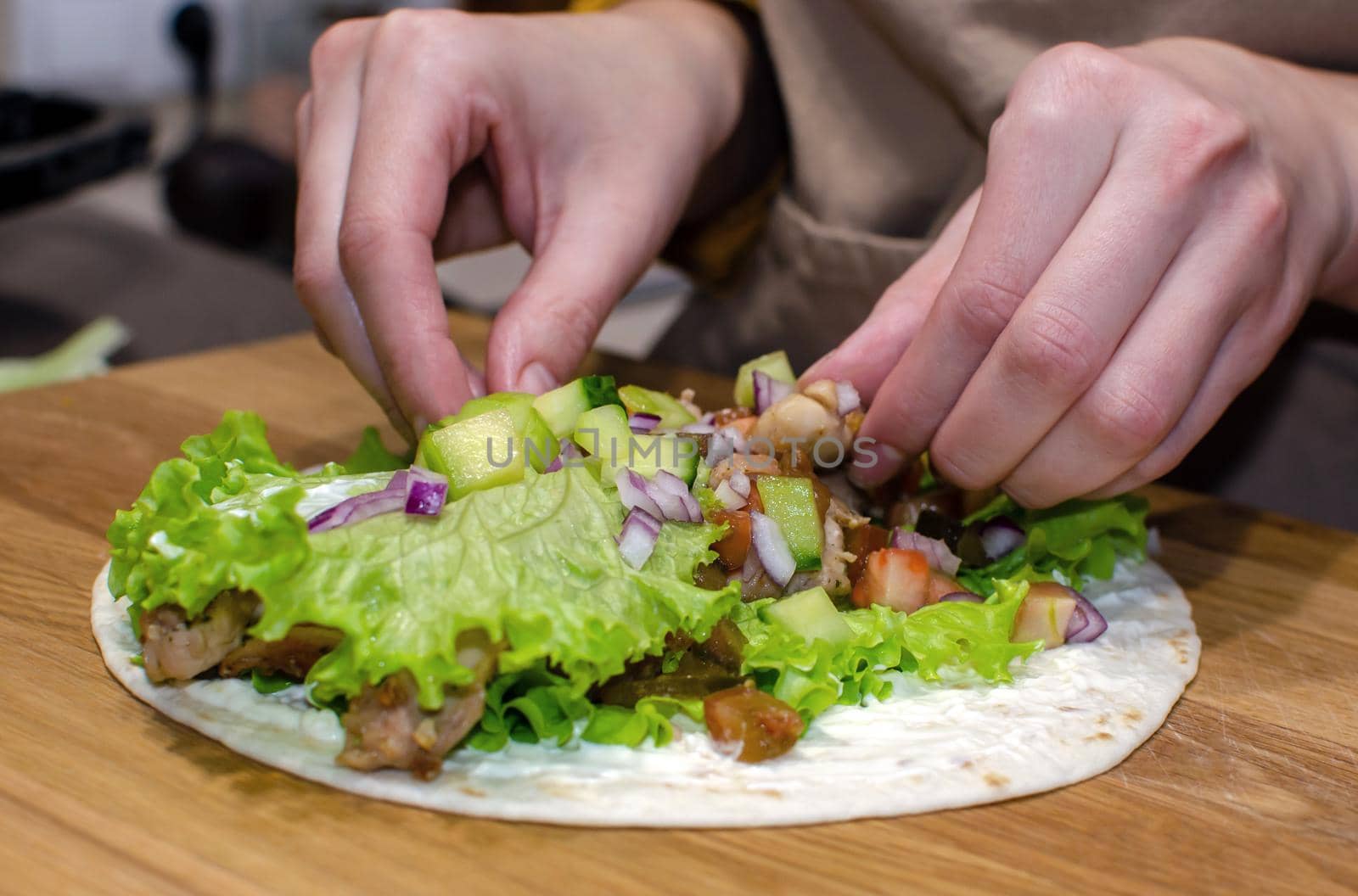 Delicious lavash rolls with fried chicken and vegetables on a wooden cutting board. Cooking process, close-up