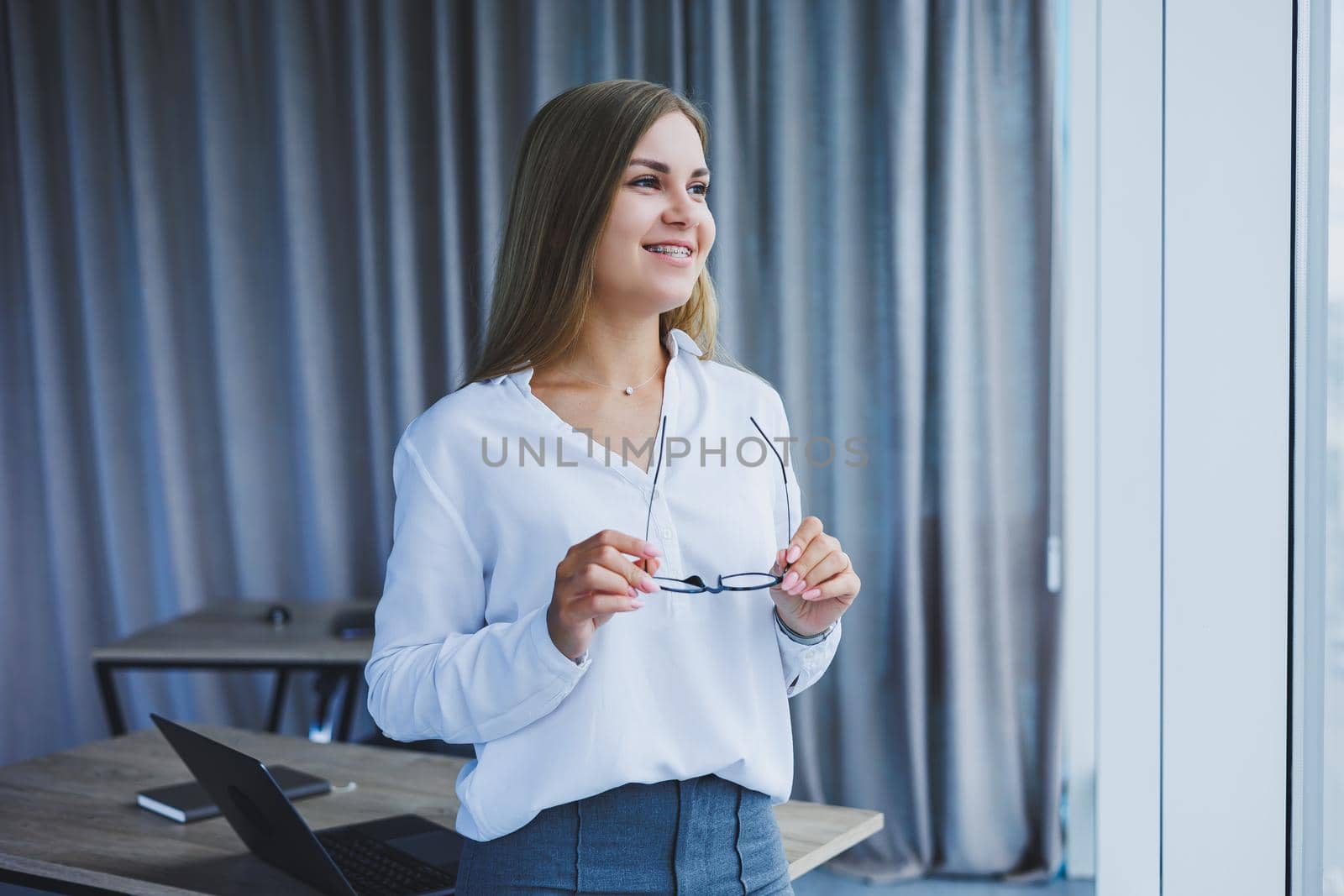 Business woman in the office with glasses in her hands. Woman manager in glasses and white shirt in the office. Working day manager